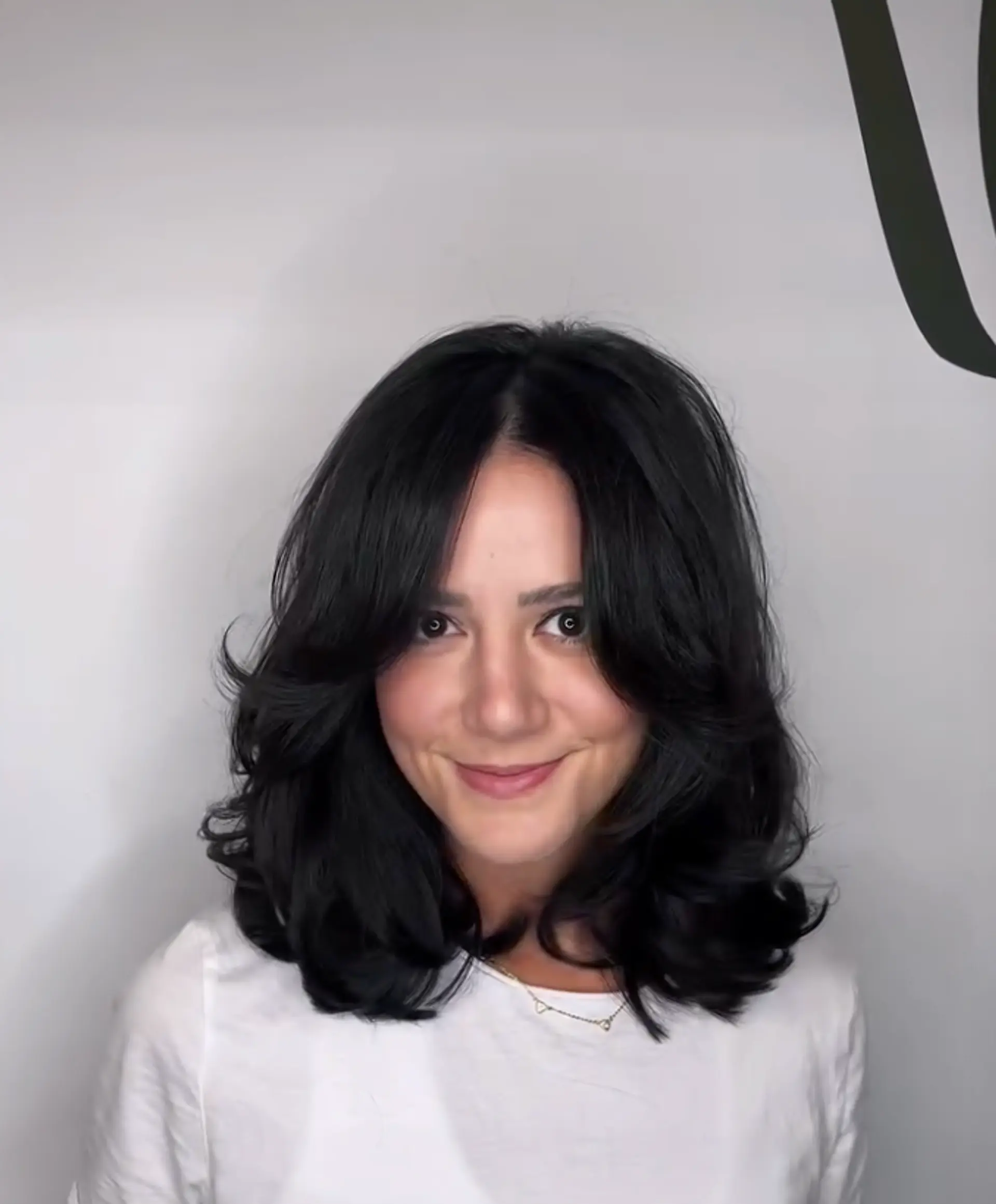 A medium length wavy hairstyle with soft, bouncy curls and layers adding volume towards the ends.

Cut and style by @juliamannino_hair
 1