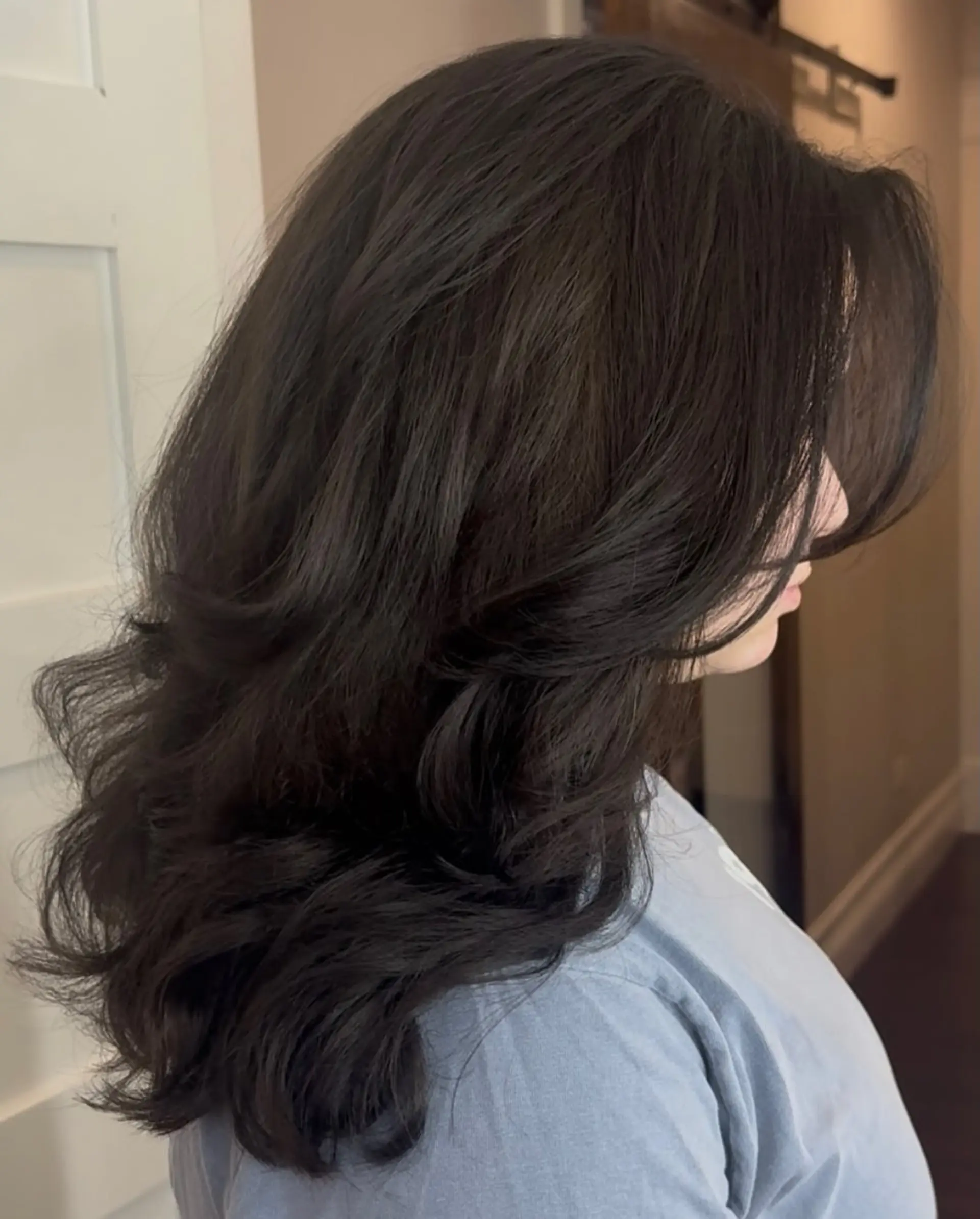 A long, voluminous dark brunette cut featuring soft face-framing layers and a bouncy blowout finish. 1