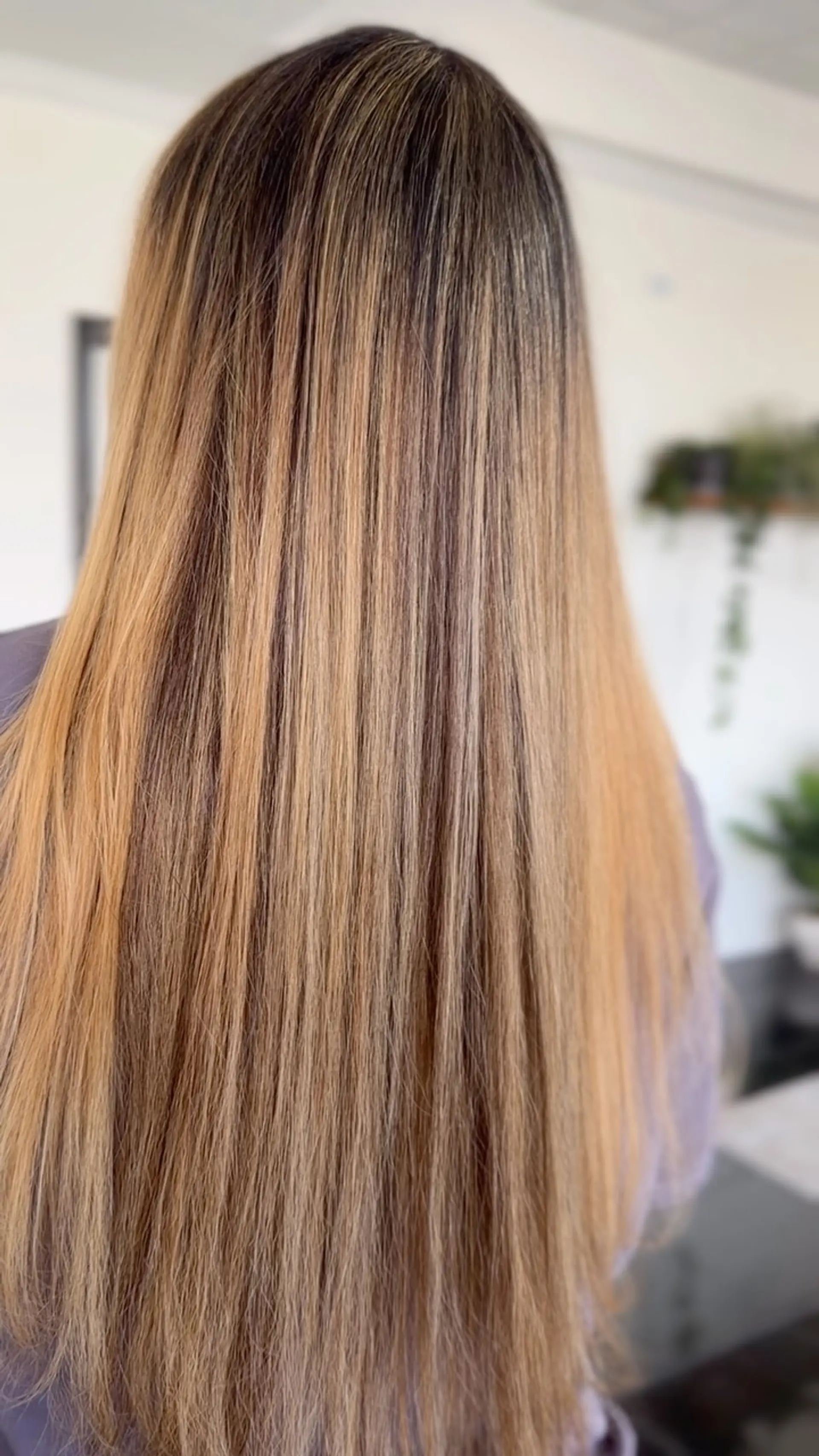 Long, straight hair featuring a warm caramel balayage blended seamlessly with natural brunette roots. 1