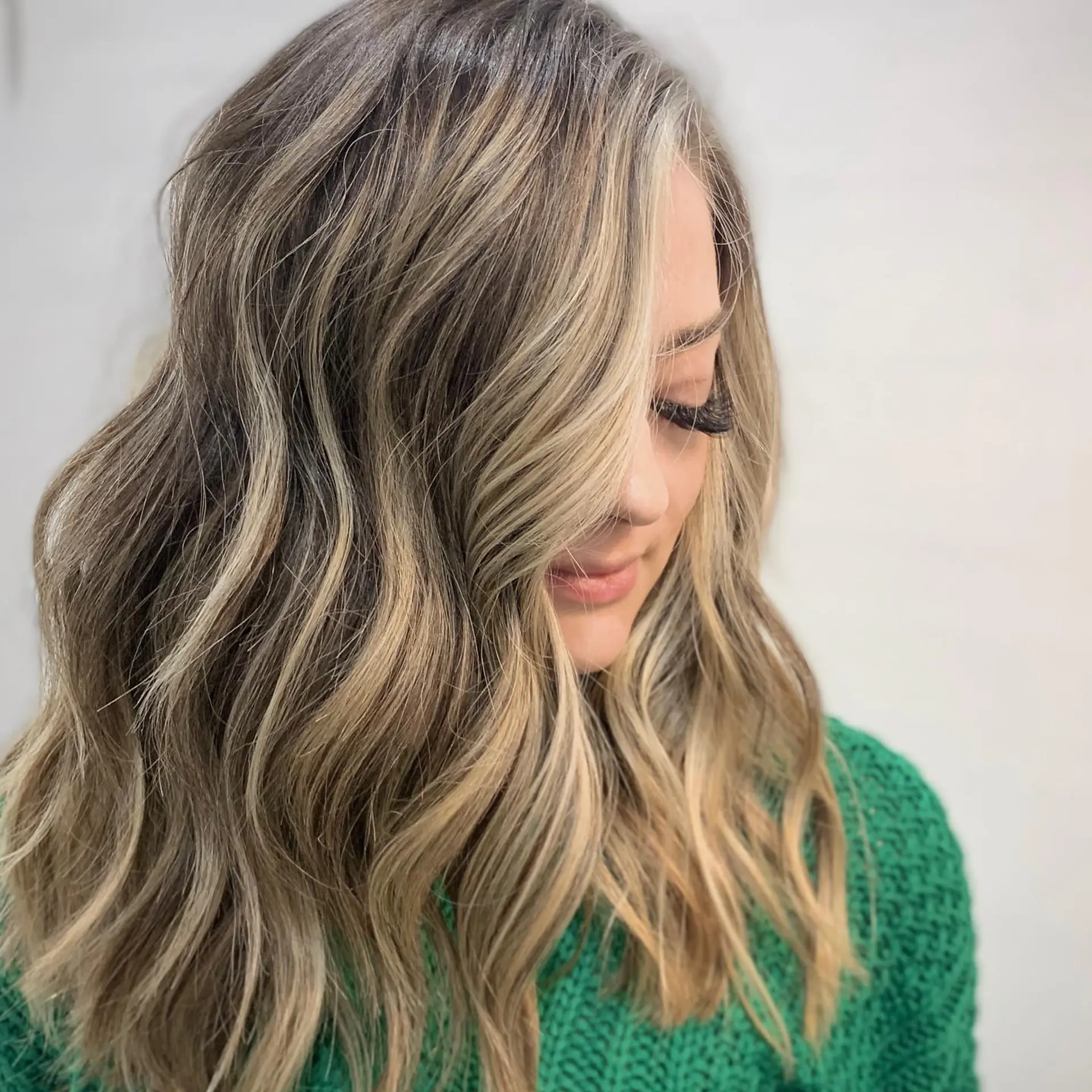 Medium-length dimensional blonde hair styled into soft, beachy waves. 1