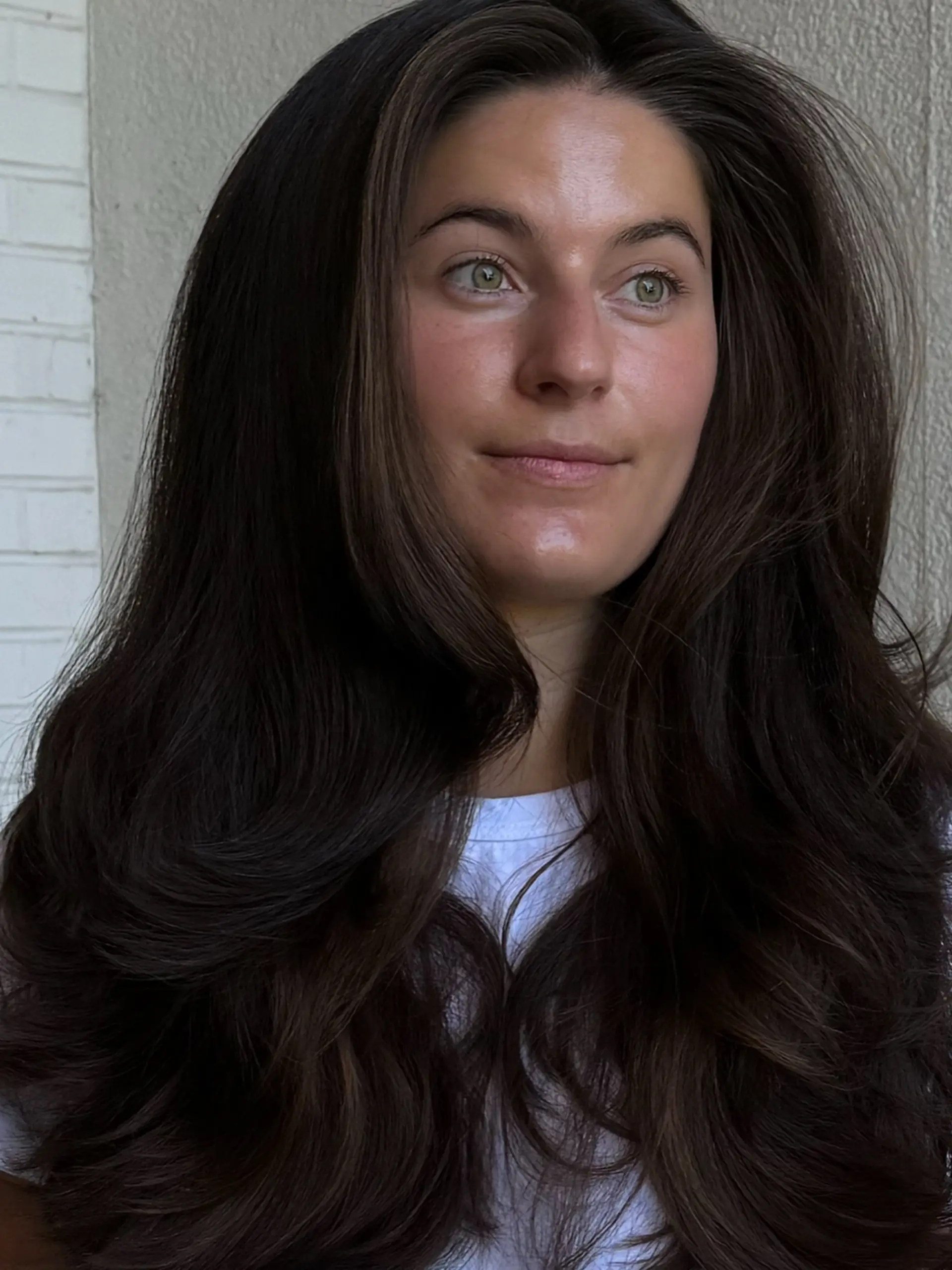 Long, thick dark brunette hair cut with soft face-framing layers and styled with a voluminous, curved blowout. 1