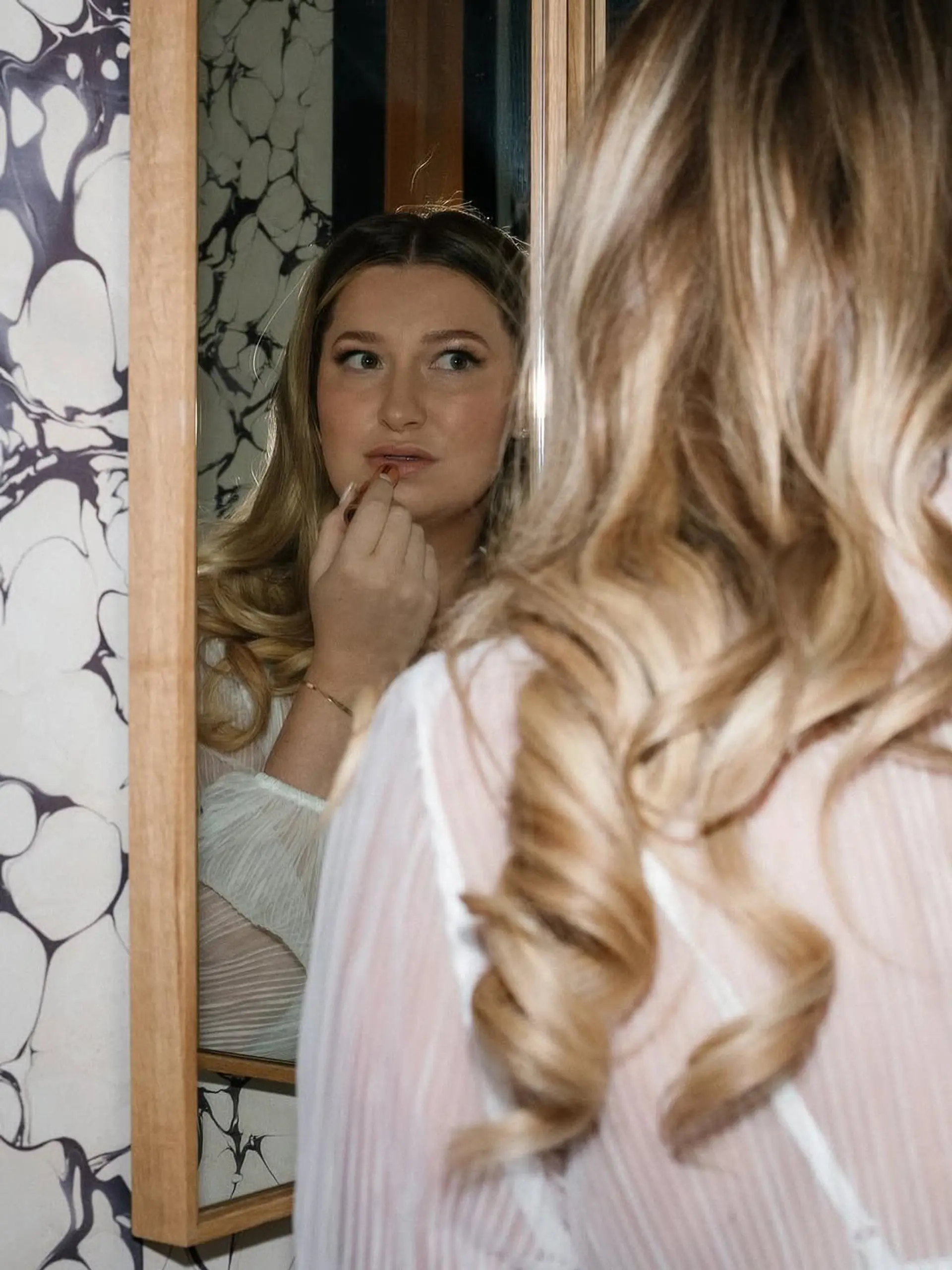 Polished, voluminous spiral curls cascading down the back on dimensional golden blonde hair. 1