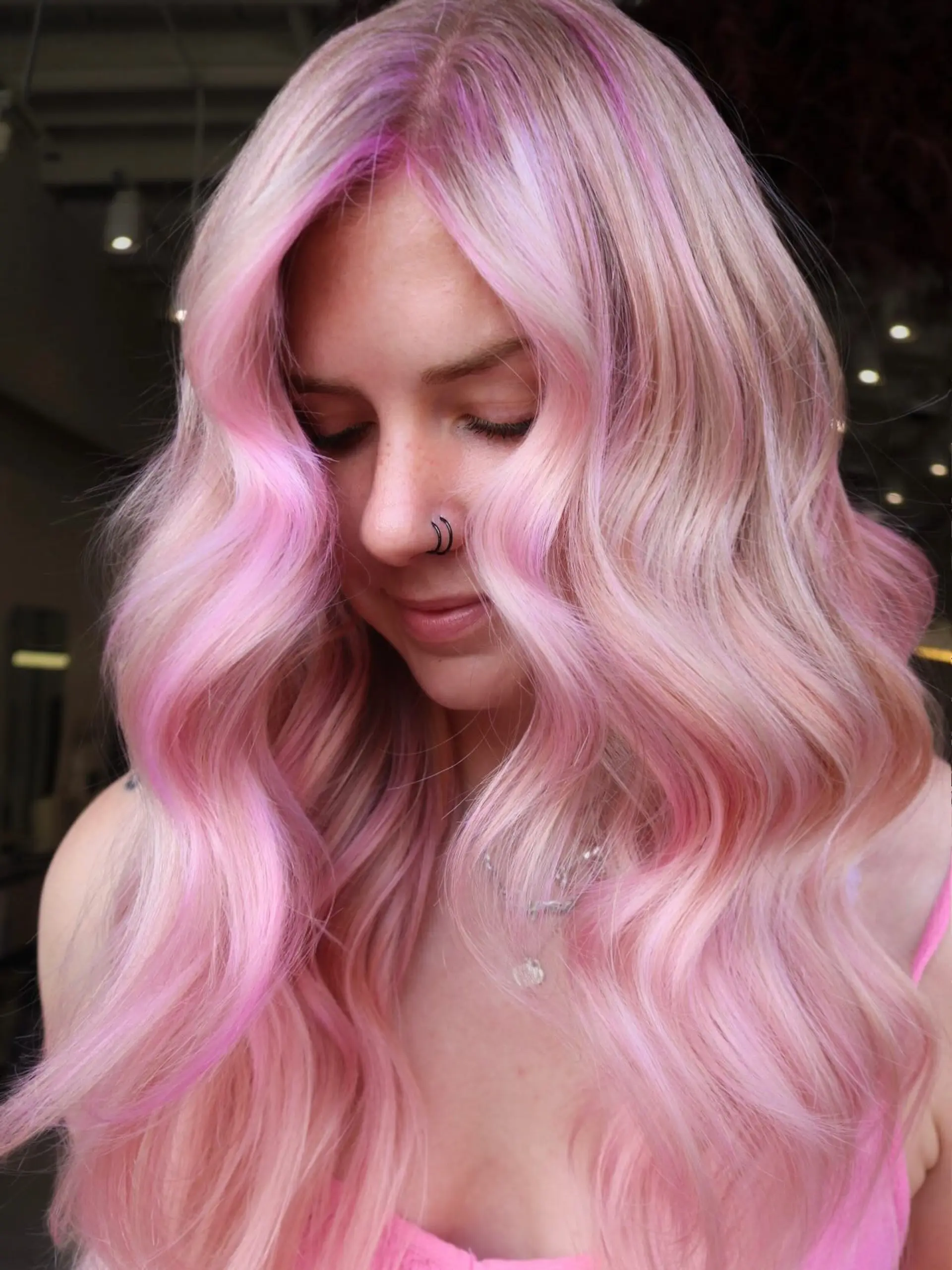 Long hair styled in soft, bouncy waves featuring a dimensional blend of pastel pink, platinum blonde, and vibrant pink face-framing highlights. 1