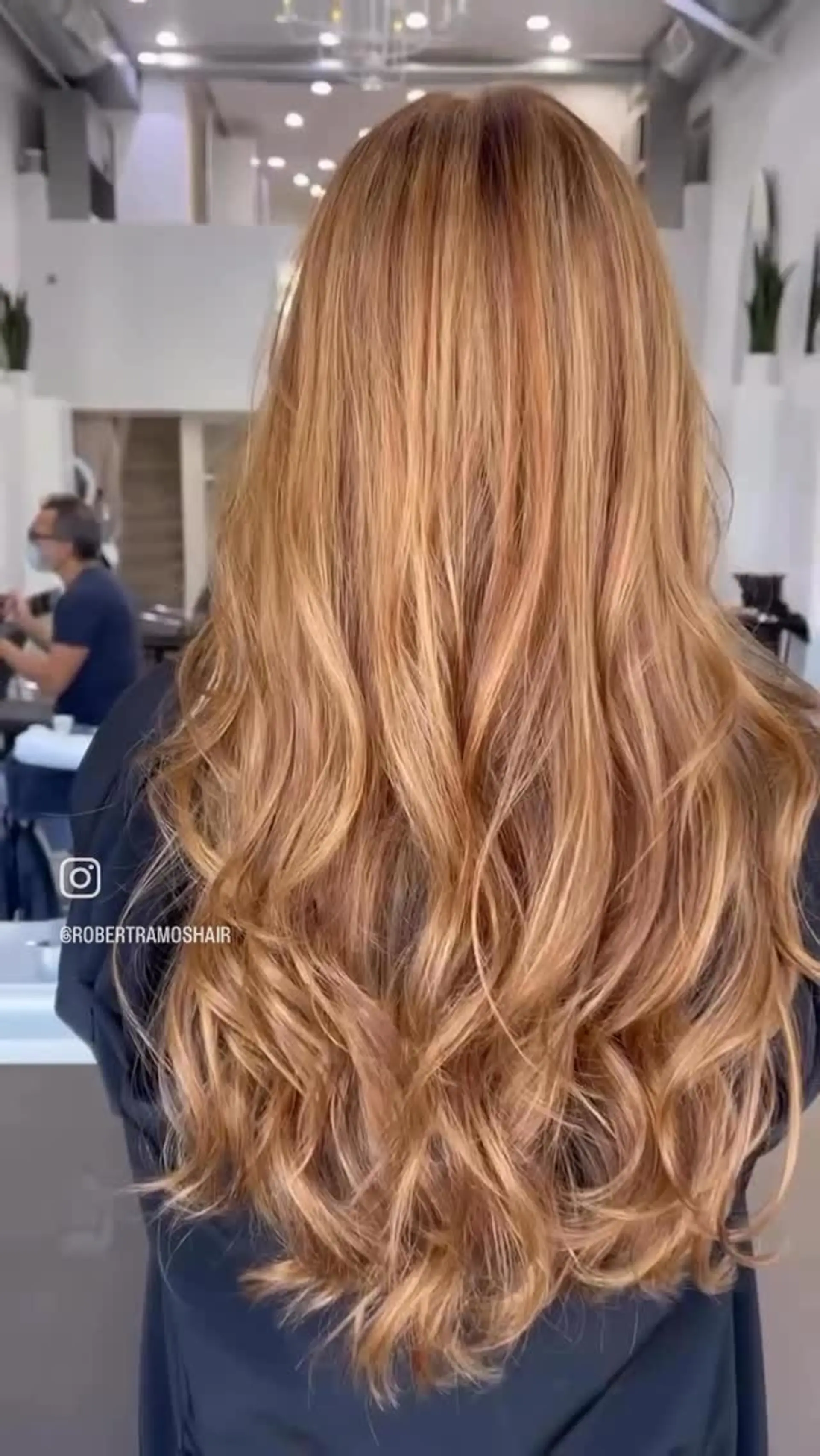 Long strawberry blonde hair featuring dimensional warm tones and styled in voluminous, cascading waves. Estimate scope: Styling only. The strawberry/copper color shown is not priced by the mapped service. Published salon-level starting/range estimate; confirm the chosen provider’s quote. 1