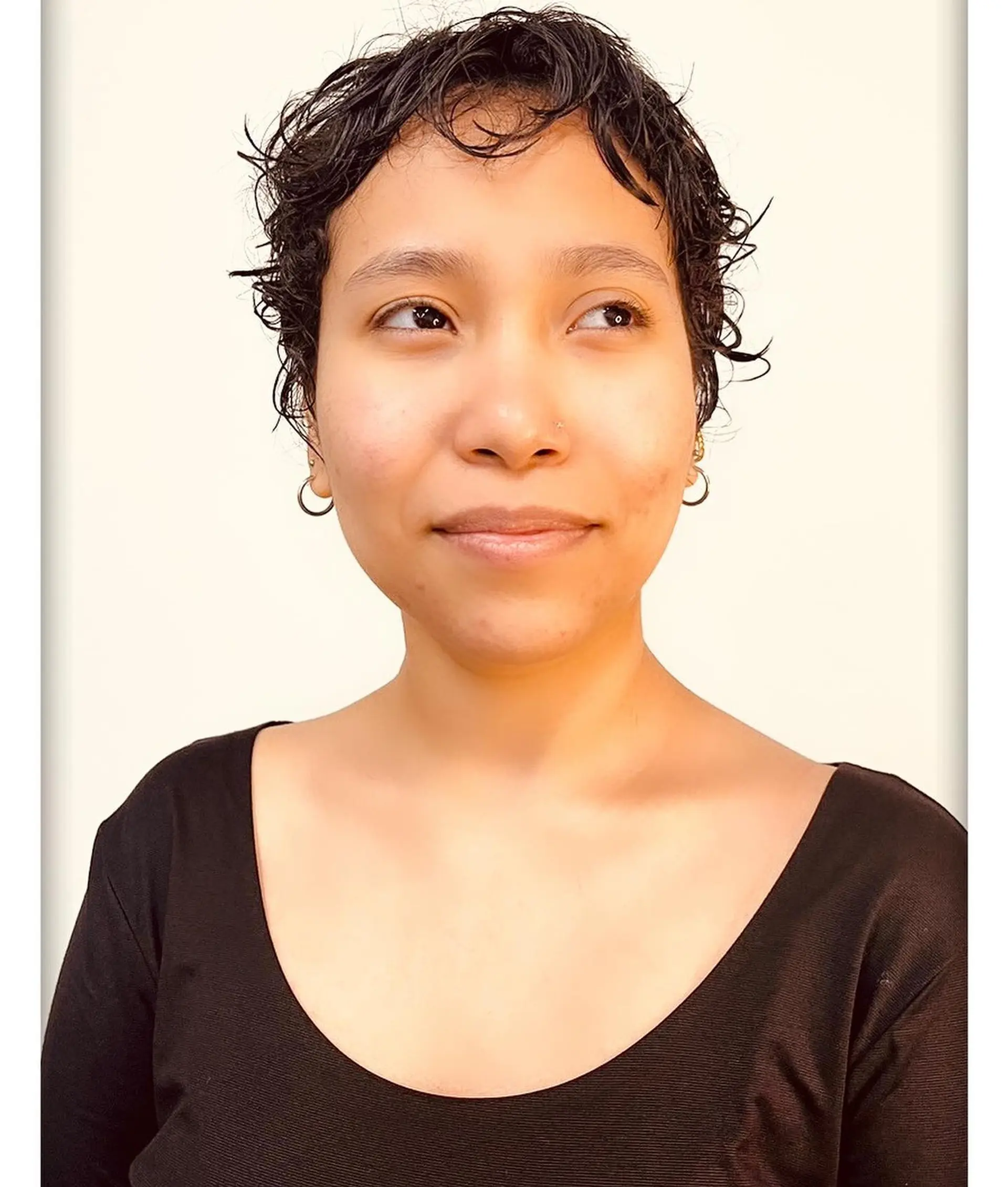 A short, textured curly pixie cut with soft piecey fringe and cropped sides. 1