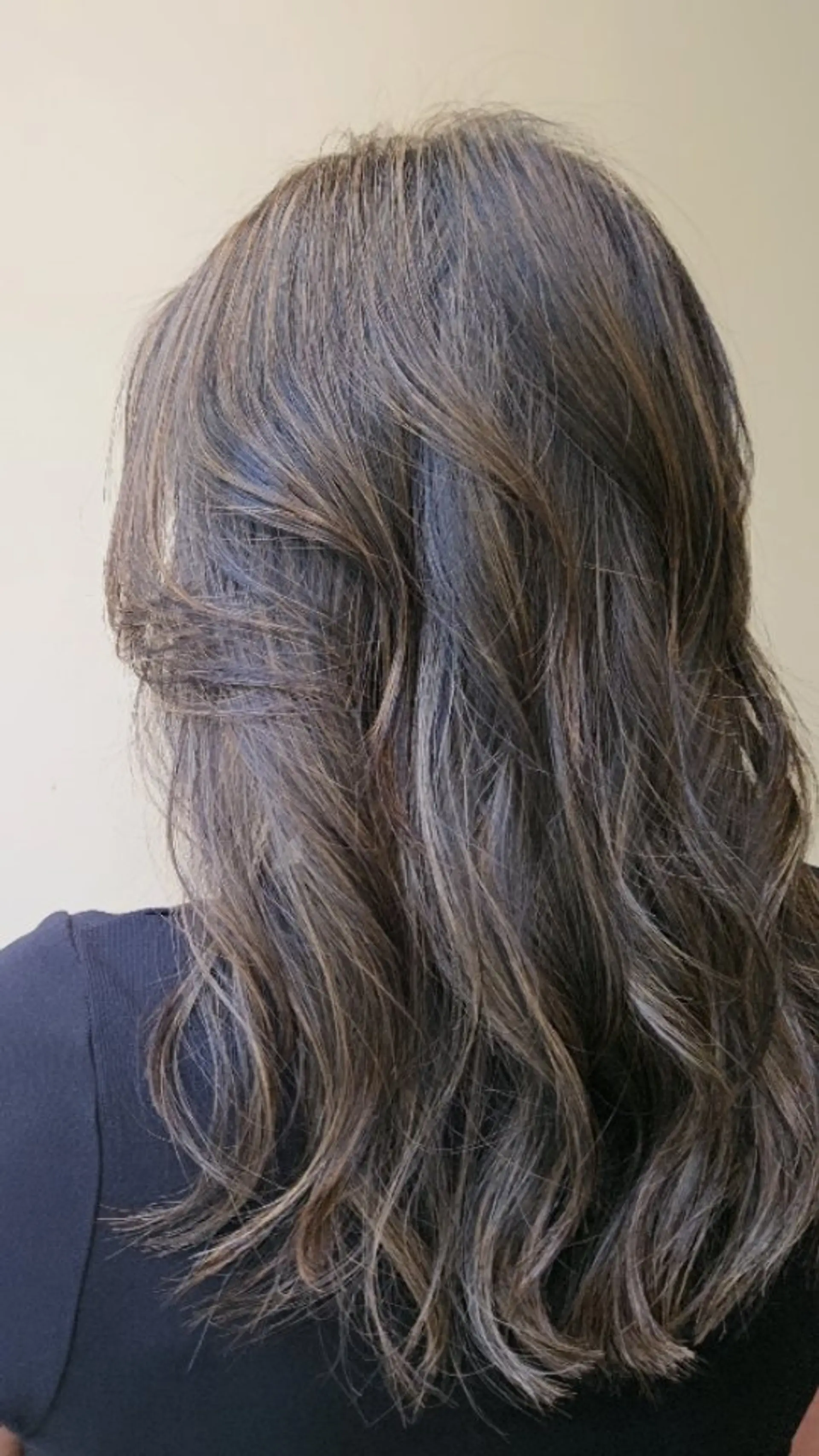 Long layered dark hair accented with subtle, fine natural highlights and styled with loose, relaxed waves. 1