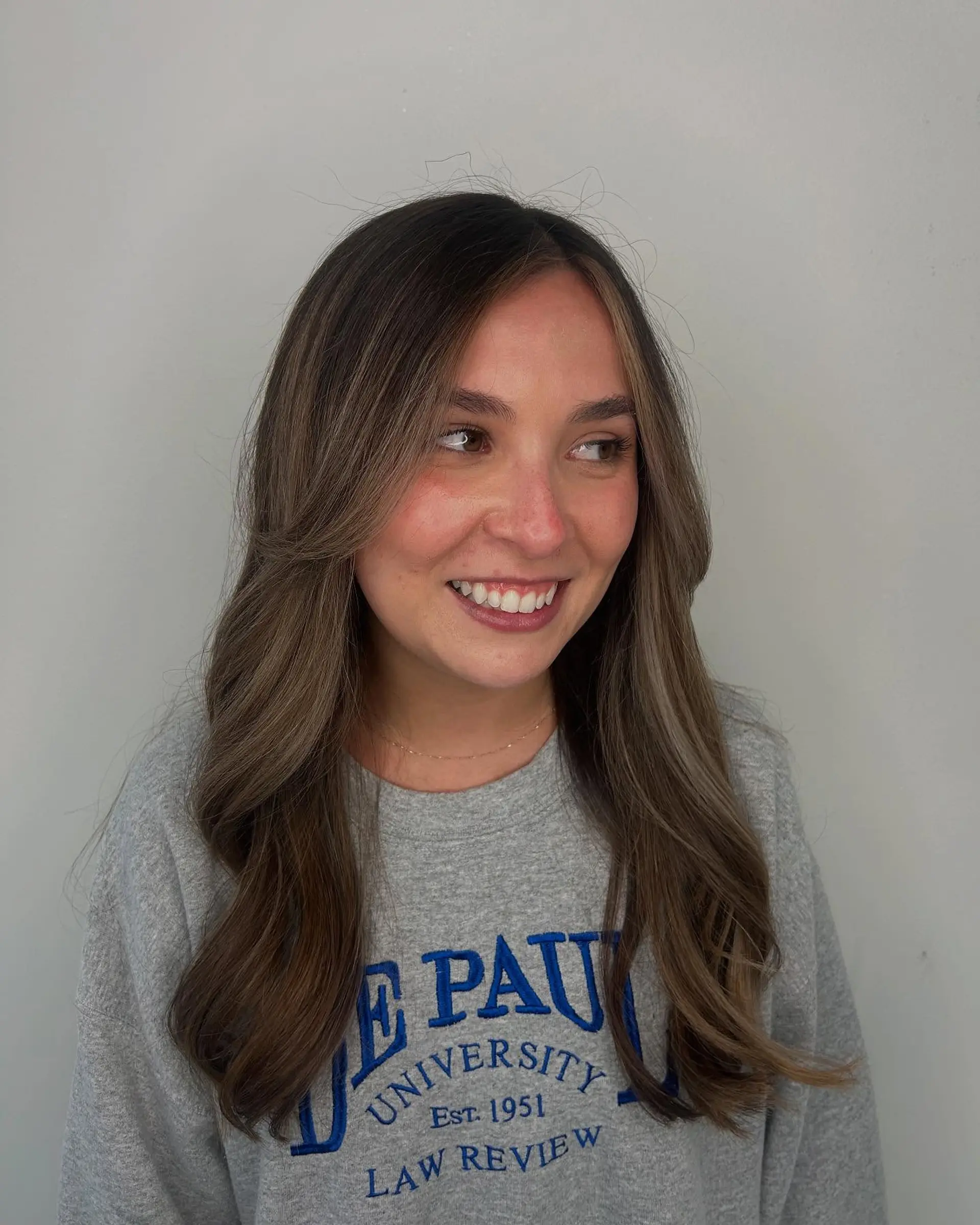 Long cool-toned brunette hair styled in loose blowout waves with subtle face-framing balayage highlights. 1