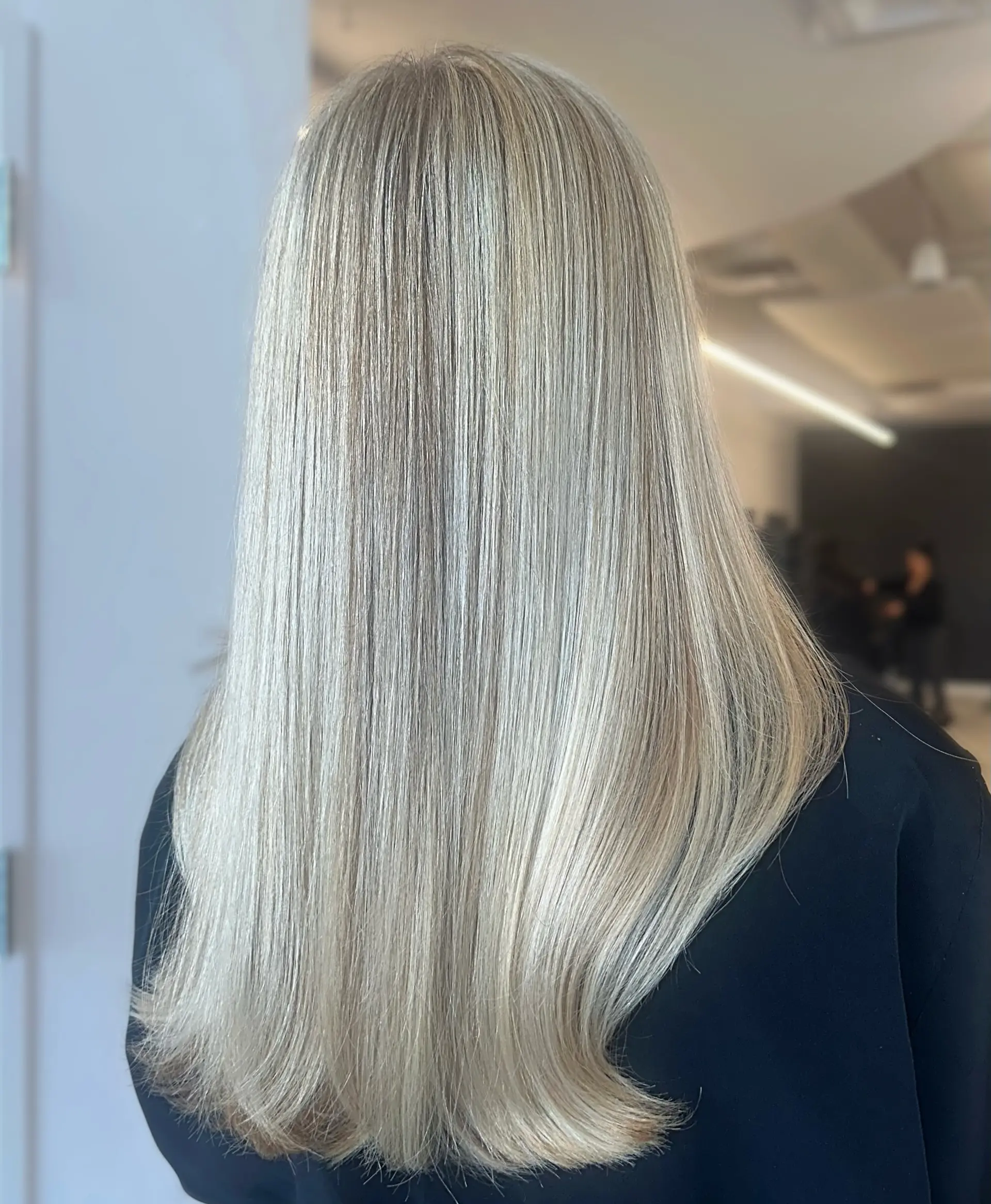 Long, straight ash blonde hair styled in a smooth, polished blowout with subtle dimension and slightly turned ends. 1