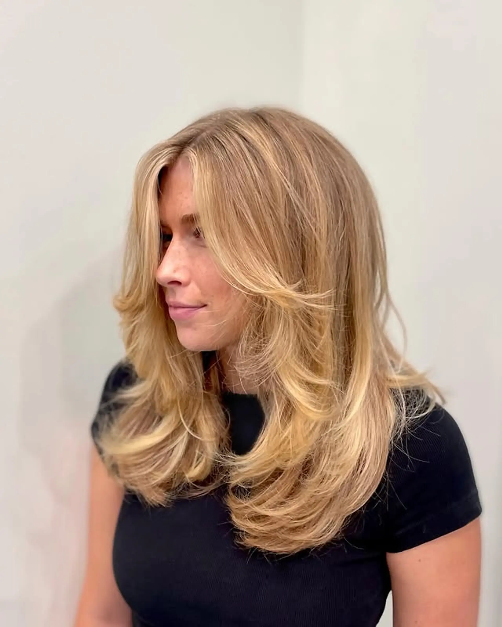 A feathered, layered haircut with flowing layers and Bardot bangs that create volume and movement. 1