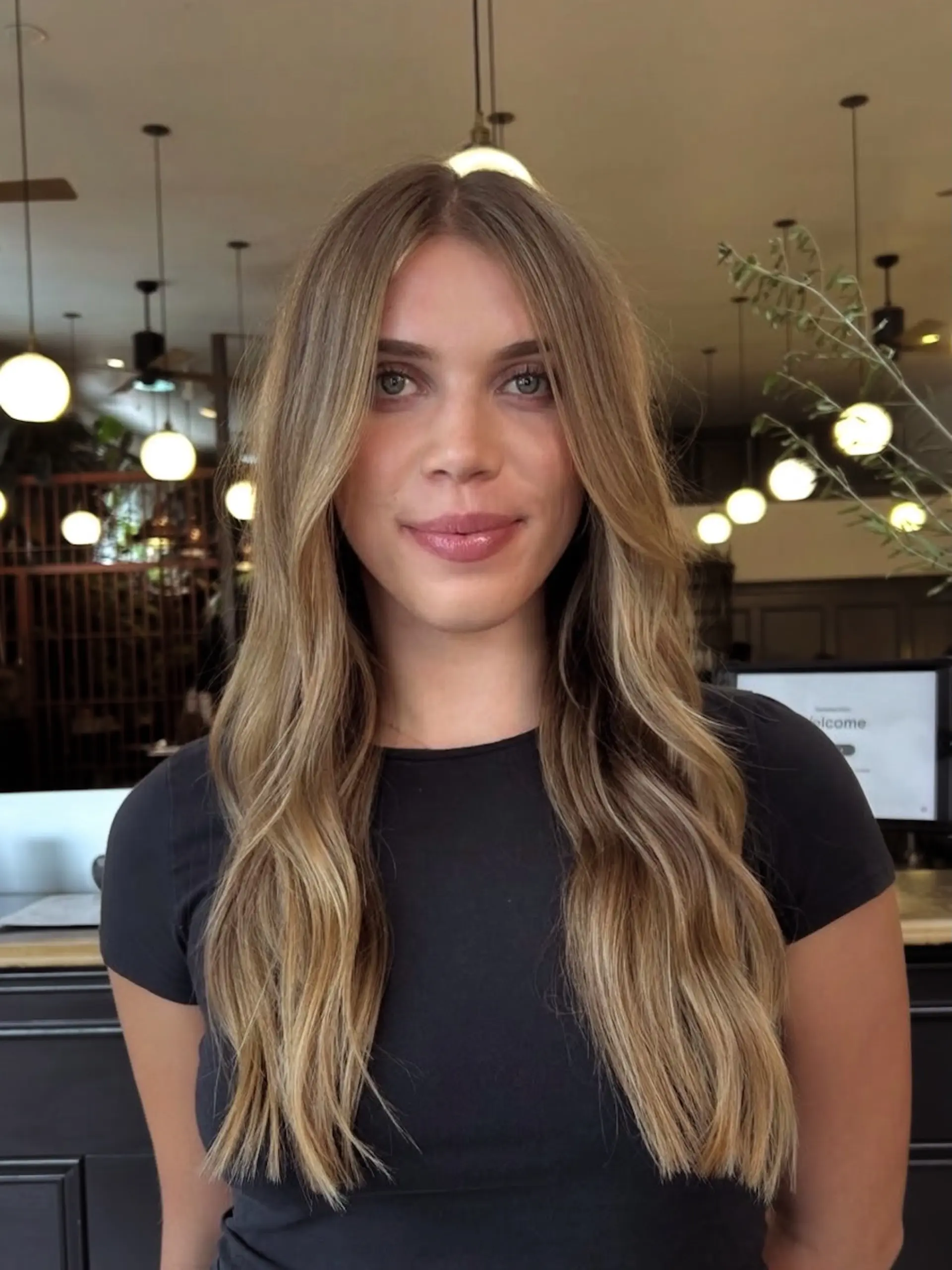 Long honey blonde hair parted down the center with subtle face-framing layers and soft waves. 1