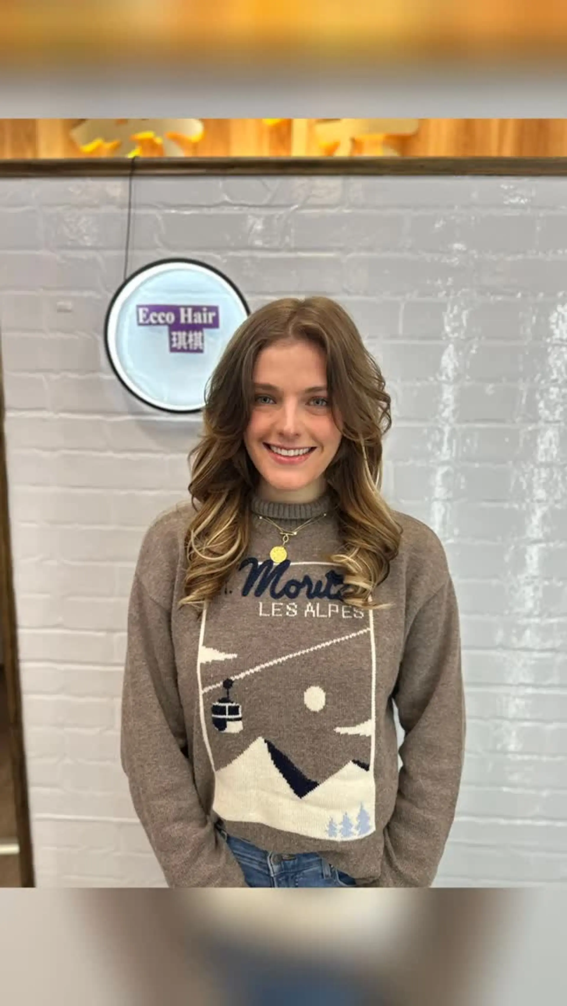 Medium-length layered hair styled in soft, bouncy waves with bright blonde highlights framing the face. 1