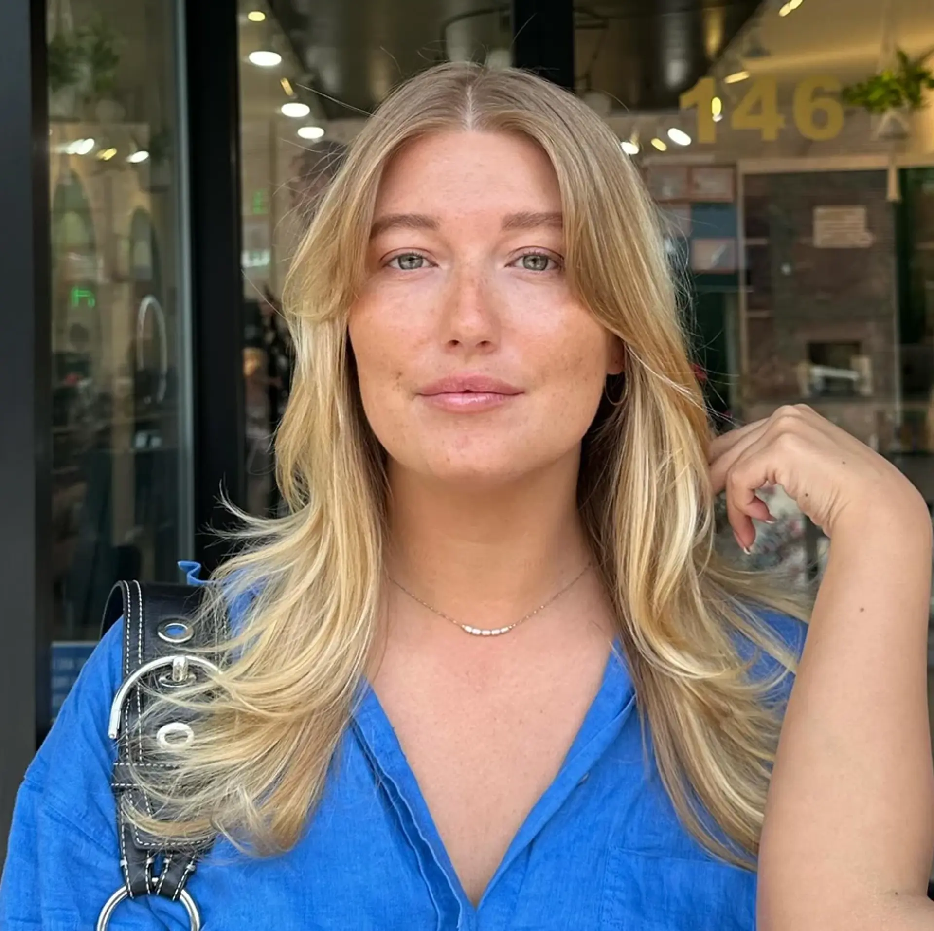 Long blonde wavy hair with a center part and layered cut. 1