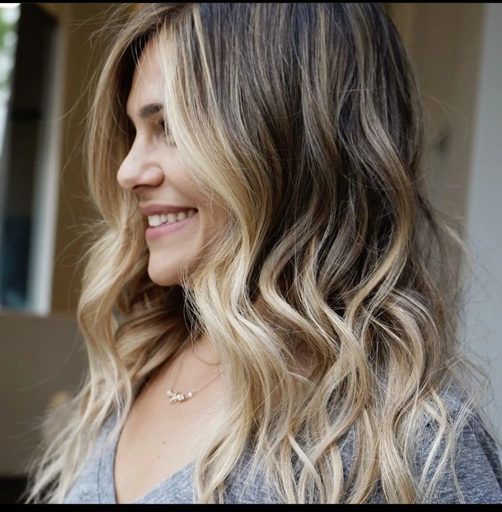 Dimensional bronde hair featuring bright face-framing blonde highlights, styled in loose, flowing waves. 1