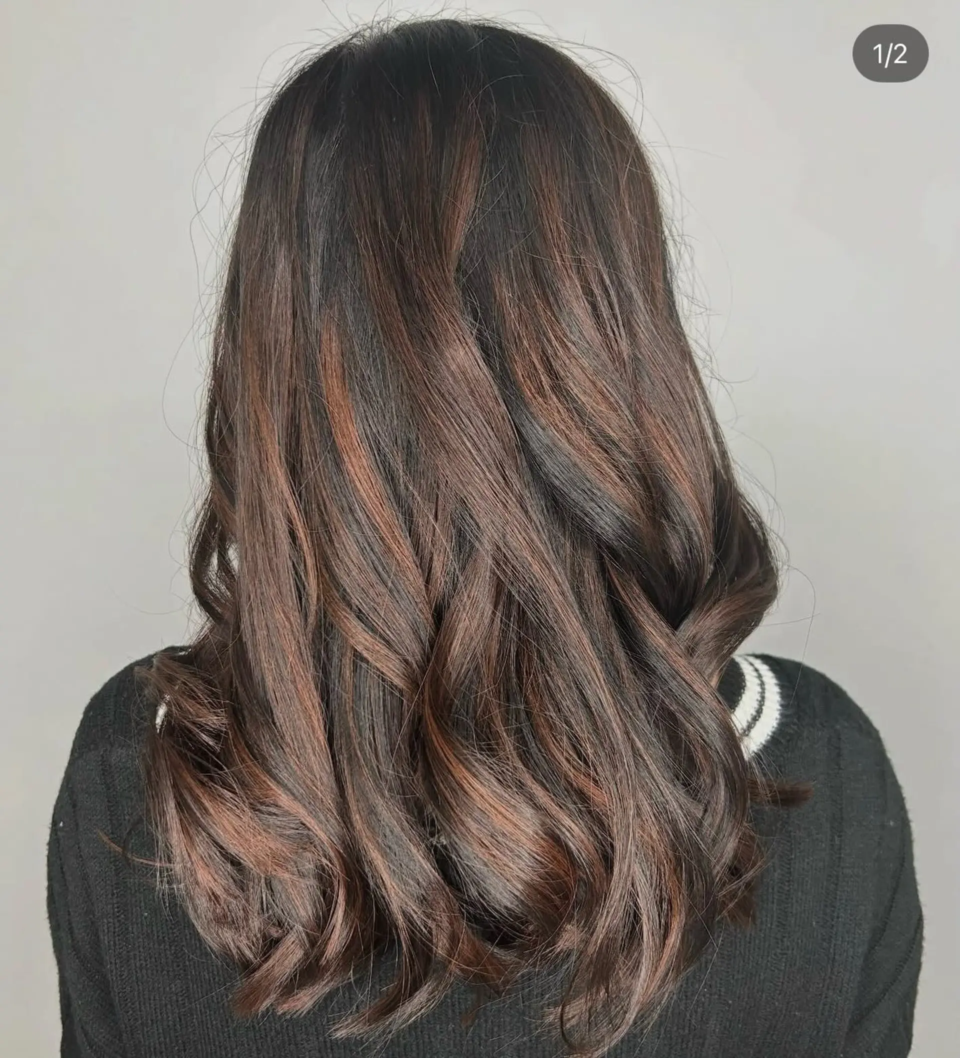 Long dark brown hair featuring warm auburn balayage highlights styled in soft, loose waves. 1