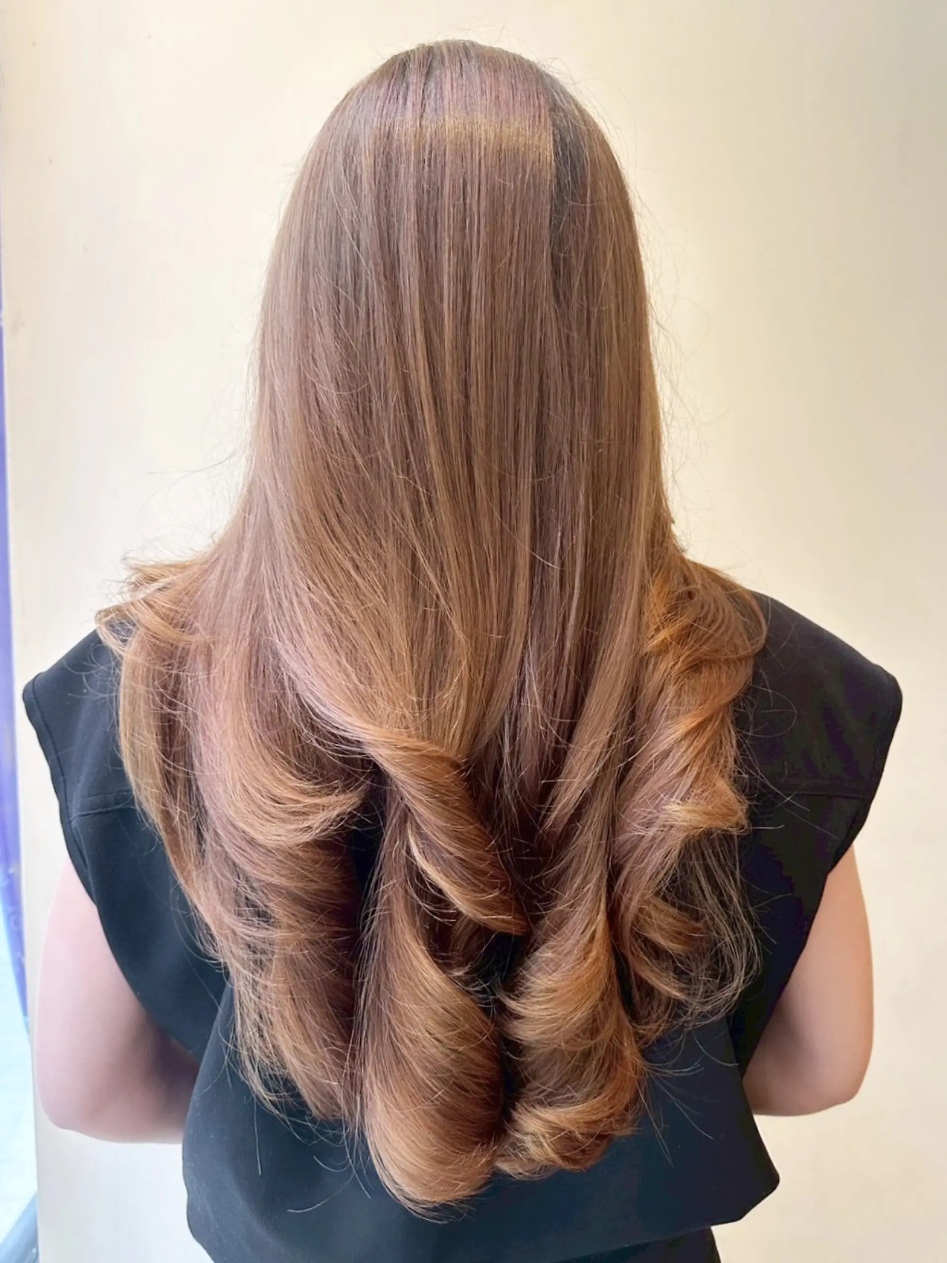 A sleek, high-shine long layered blowout featuring voluminous curled ends. 1