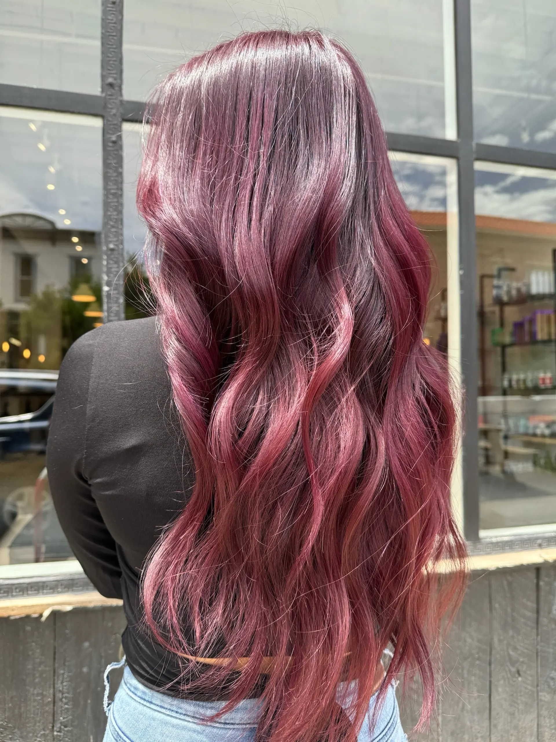 Long wavy hairstyle featuring a vivid transition from natural dark roots into rich berry, magenta, and plum tones. 1