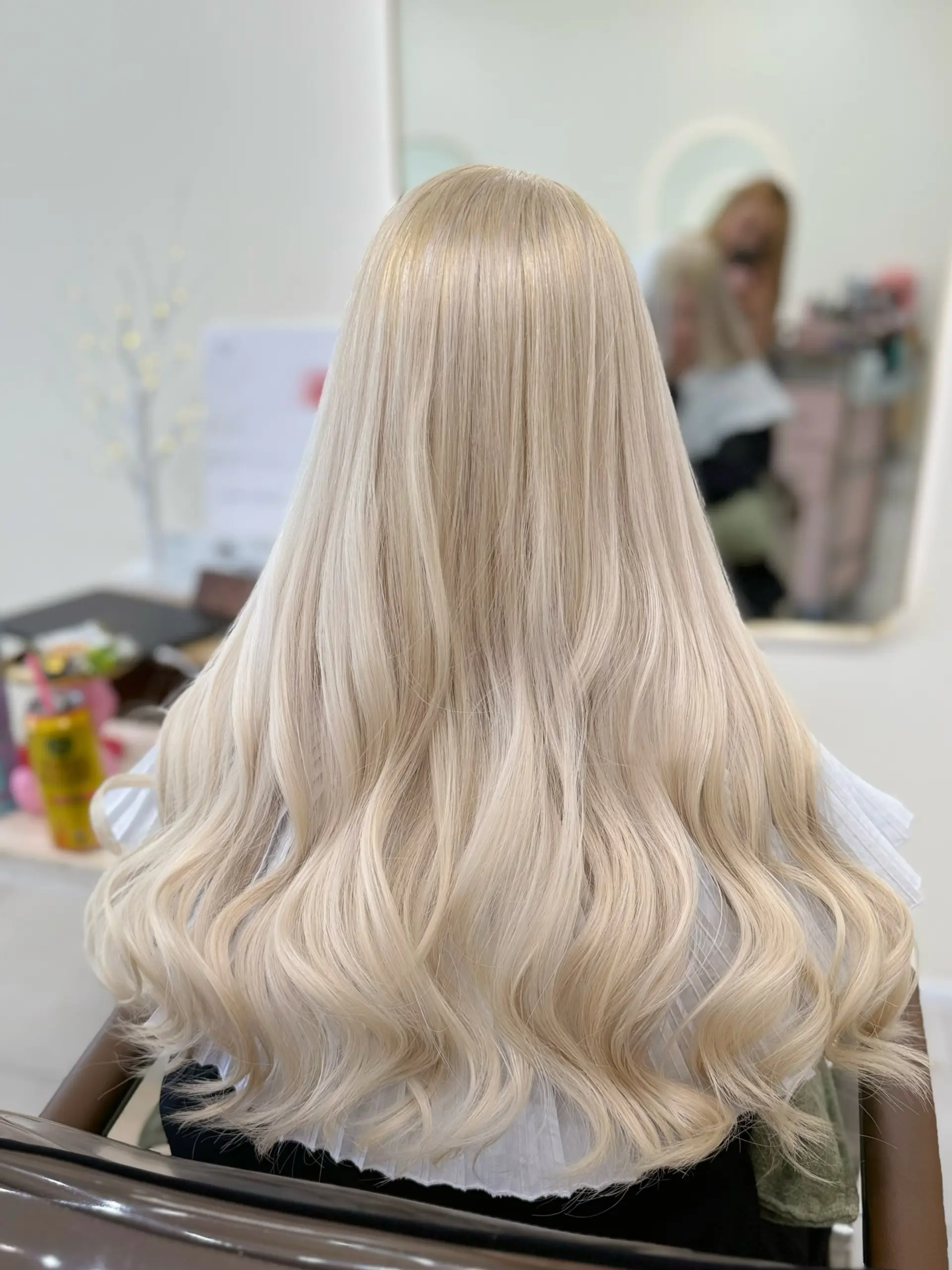 Ultra-light platinum blonde hair styled with smooth length and soft, voluminous waves throughout the lower ends. 1