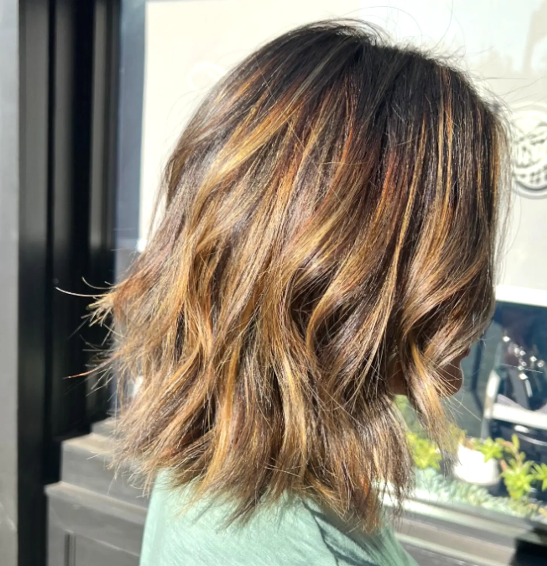 A medium-length wavy bob with caramel and blonde balayage highlights, styled with textured waves. 1
