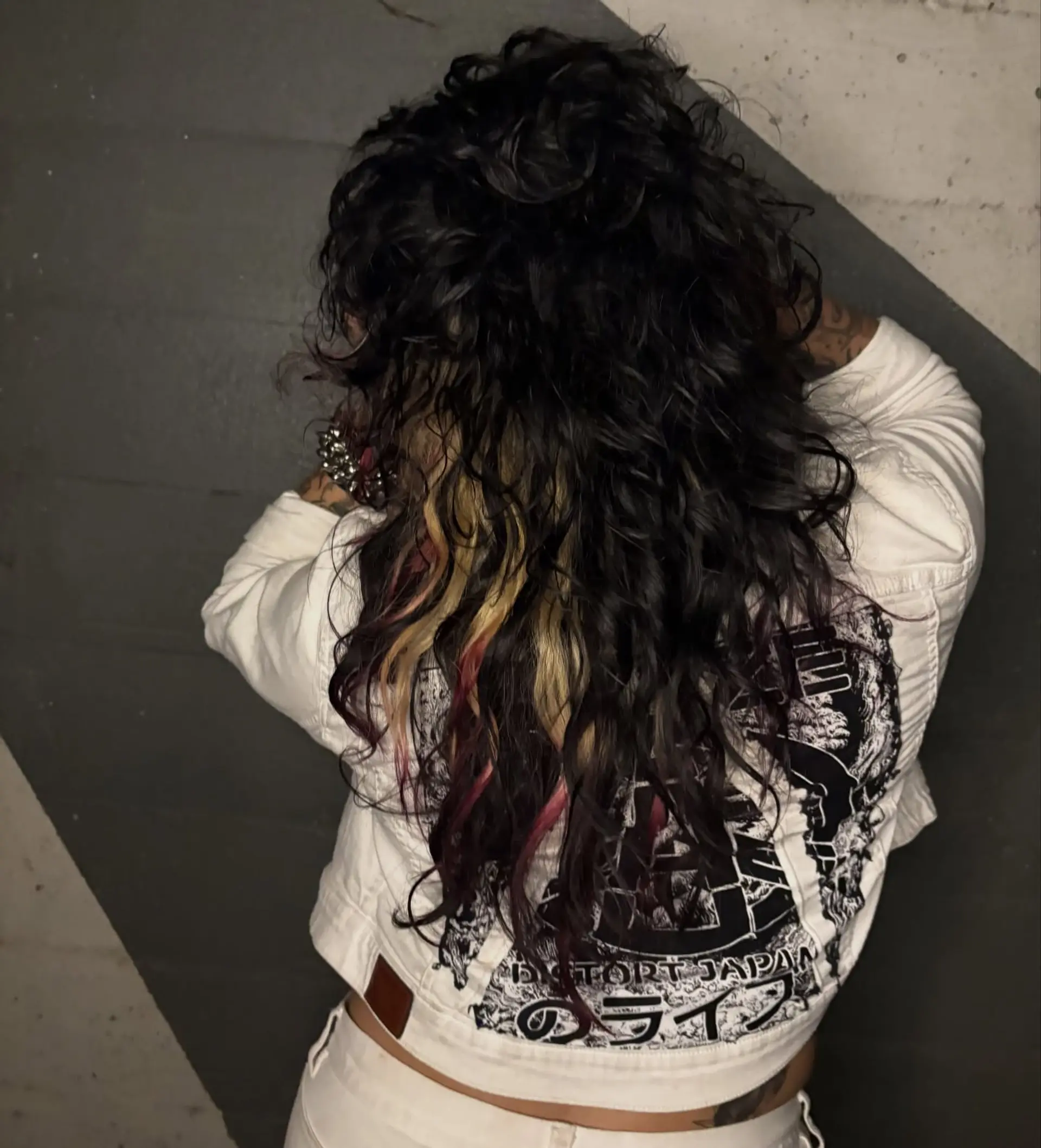 A textured curly shag featuring dark curls contrasted with peekaboo blonde panels and raspberry pink tips. 1