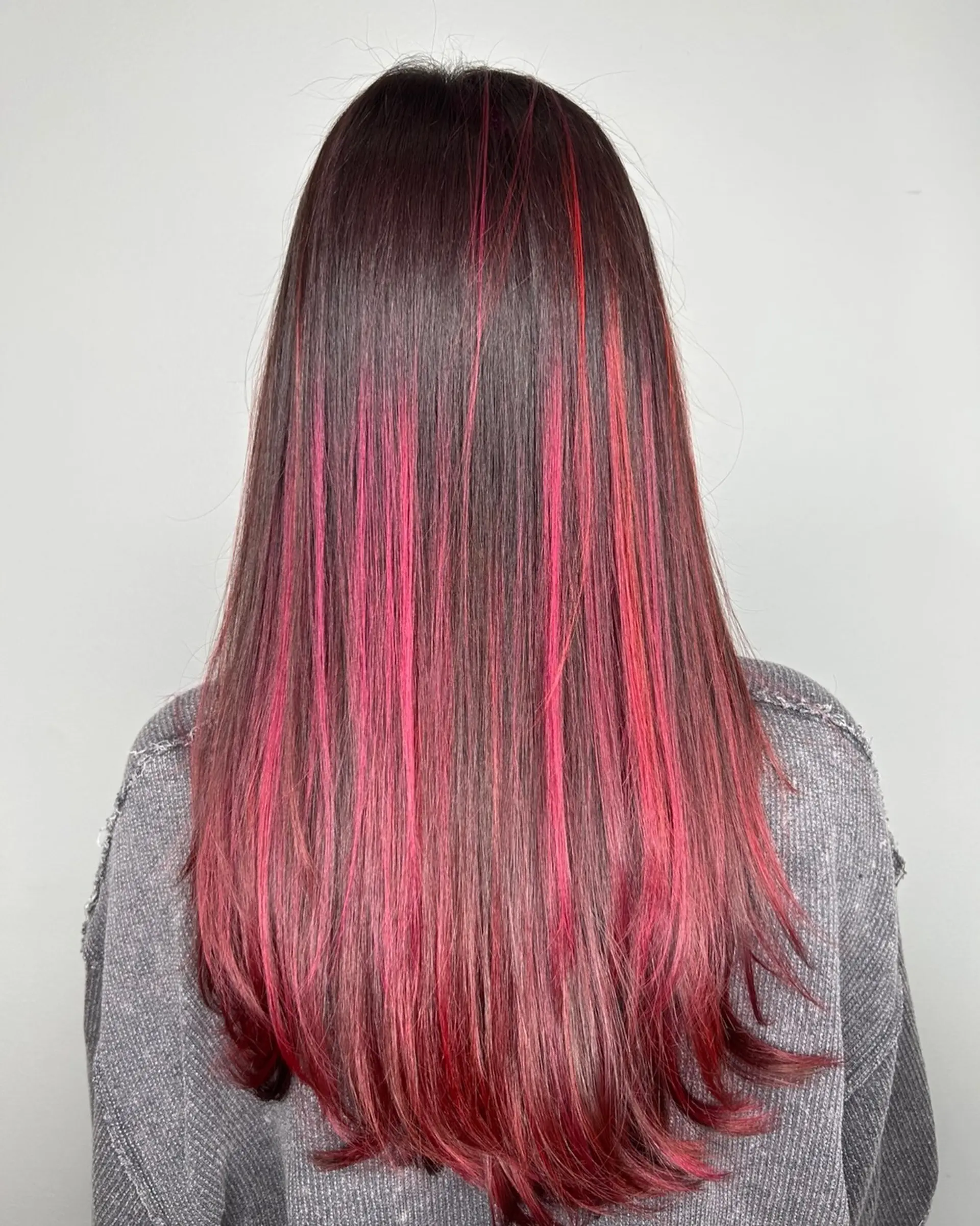 Long straight dark hair accented with vivid magenta and bright pink balayage highlights. 1