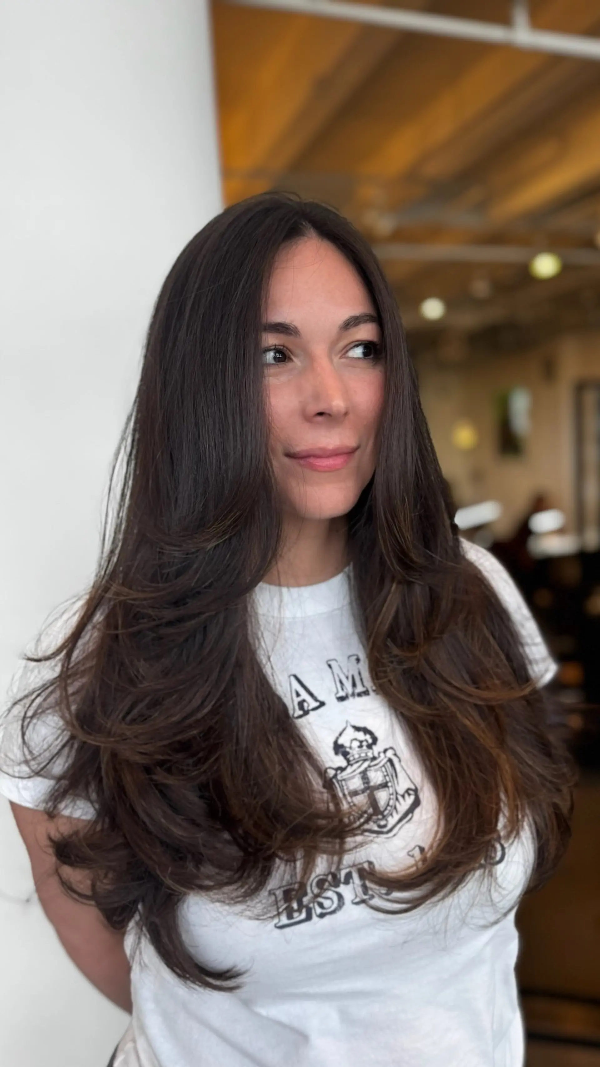 Long dark brown hair featuring sweeping face-framing layers styled into a voluminous, bouncy blowout. 1