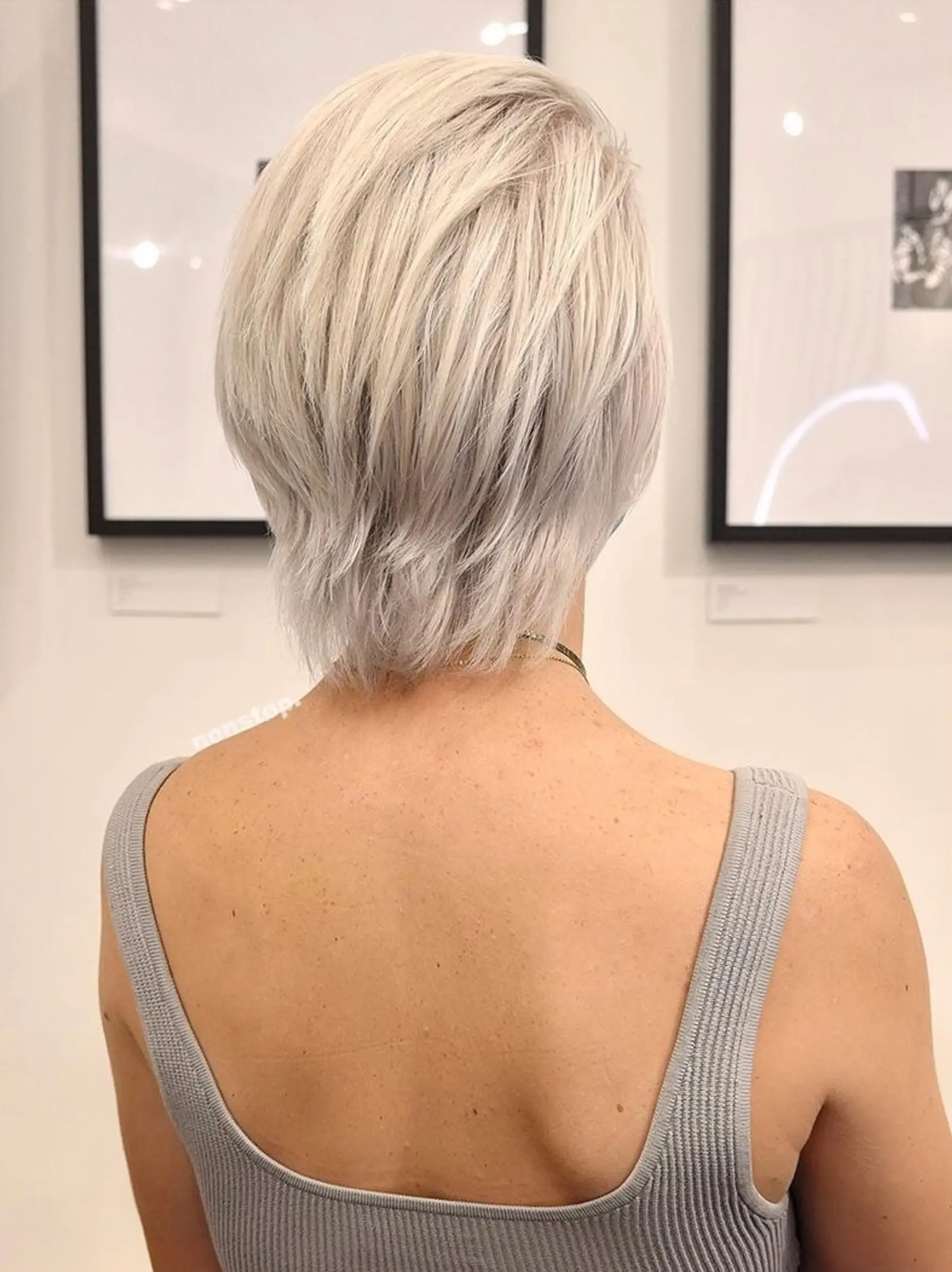 A medium-length, platinum blonde with silver hues hairstyle. The straight hair is side-parted, featuring layers and feathered ends for texture and movement, presenting a sleek and sophisticated look. 👩🏼 Hair by @dynocuts 👩🏼 2