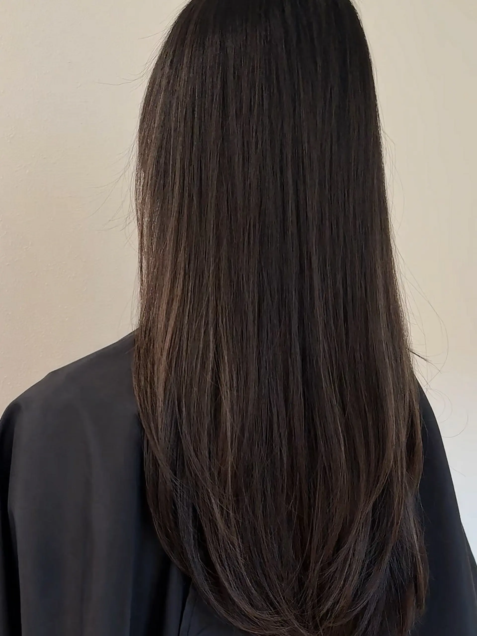 Long straight dark brunette hair cut with subtle face-framing and curved long layers at the ends. 1
