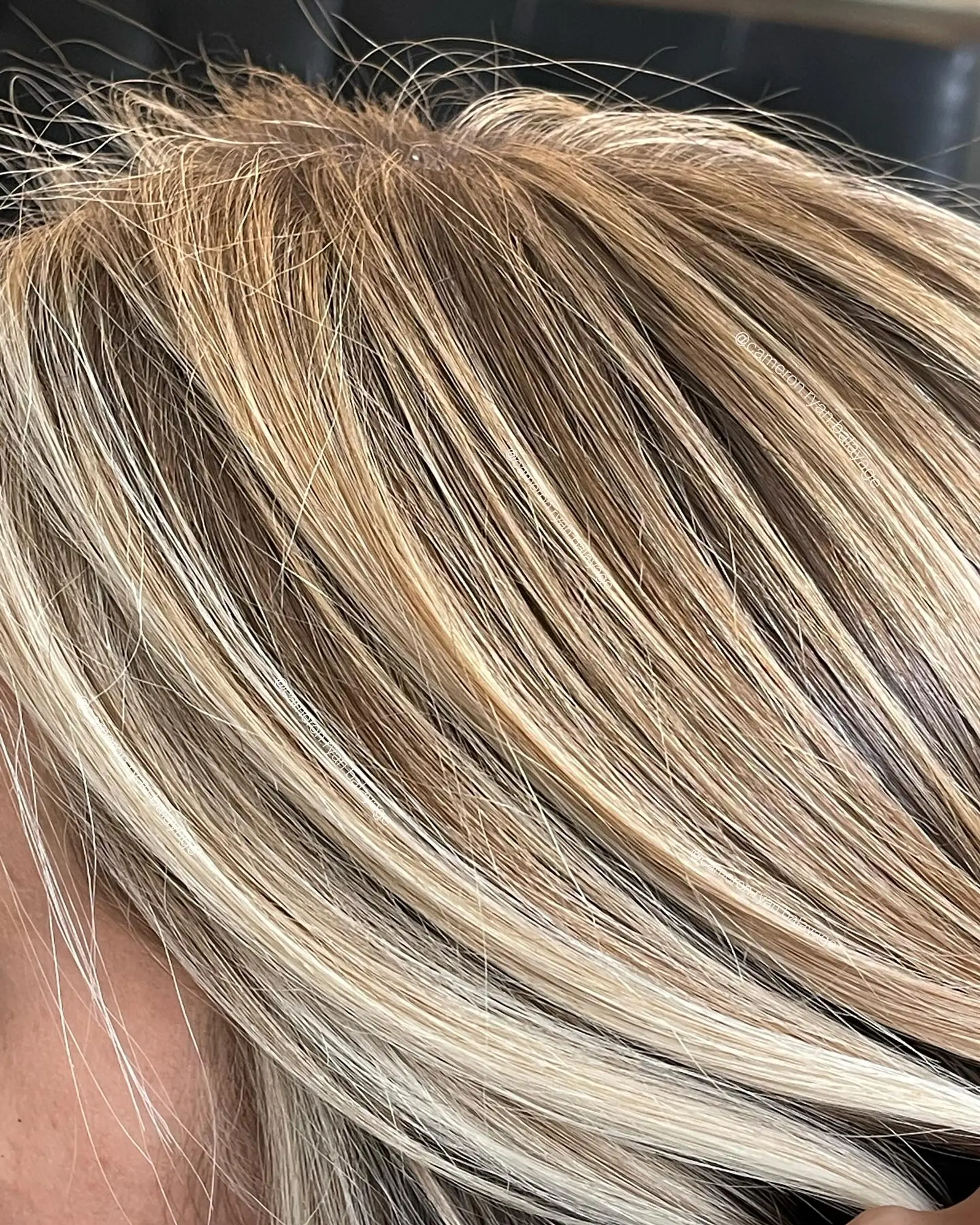 A close-up view of finely woven blonde face-framing highlights blended into natural light brown hair. 1