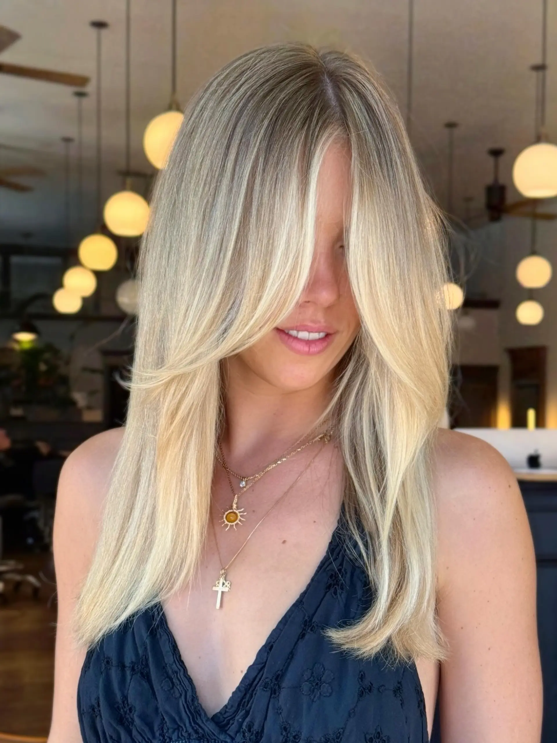 Long dimensional blonde hair styled straight with voluminous face-framing curtain layers. 1