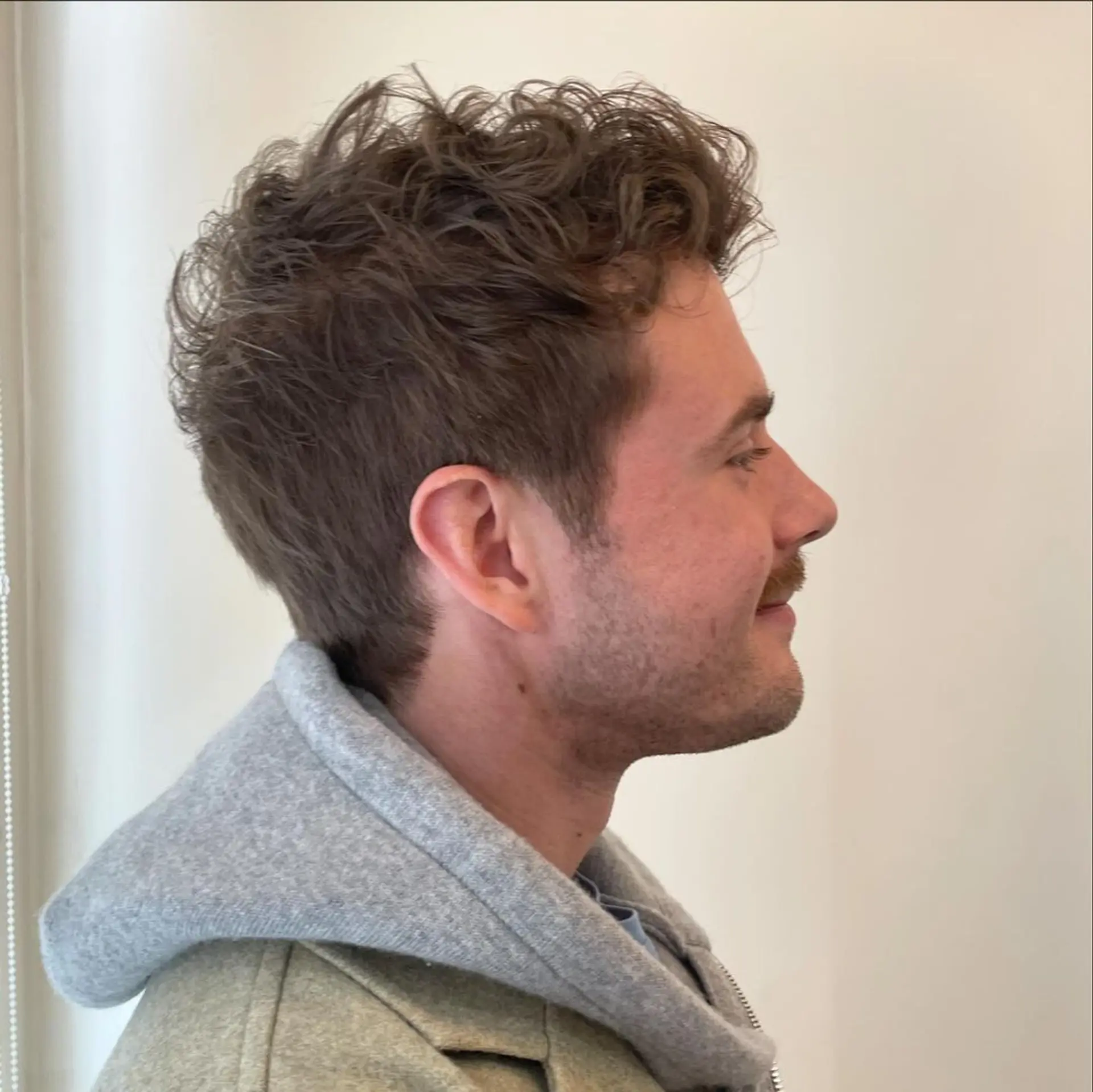 A short, curly hairstyle with a textured top and neatly trimmed sides, showcasing natural curls in a casual yet refined manner. 2