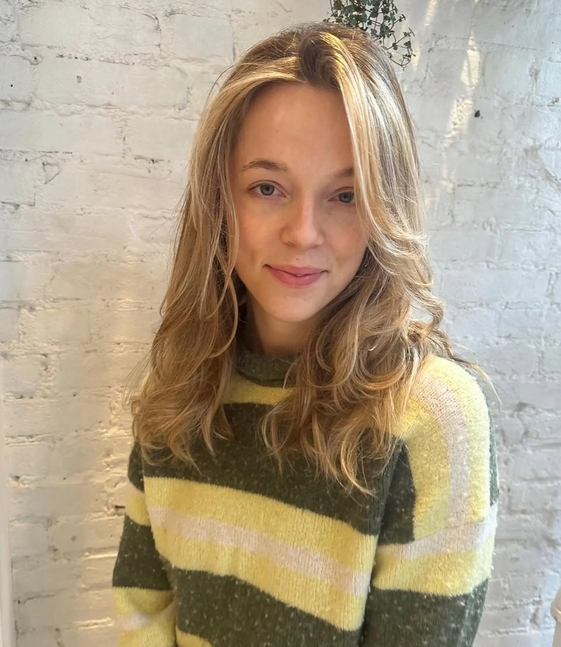 A medium-length wavy hairstyle with curtain bangs and face-framing layers. 1