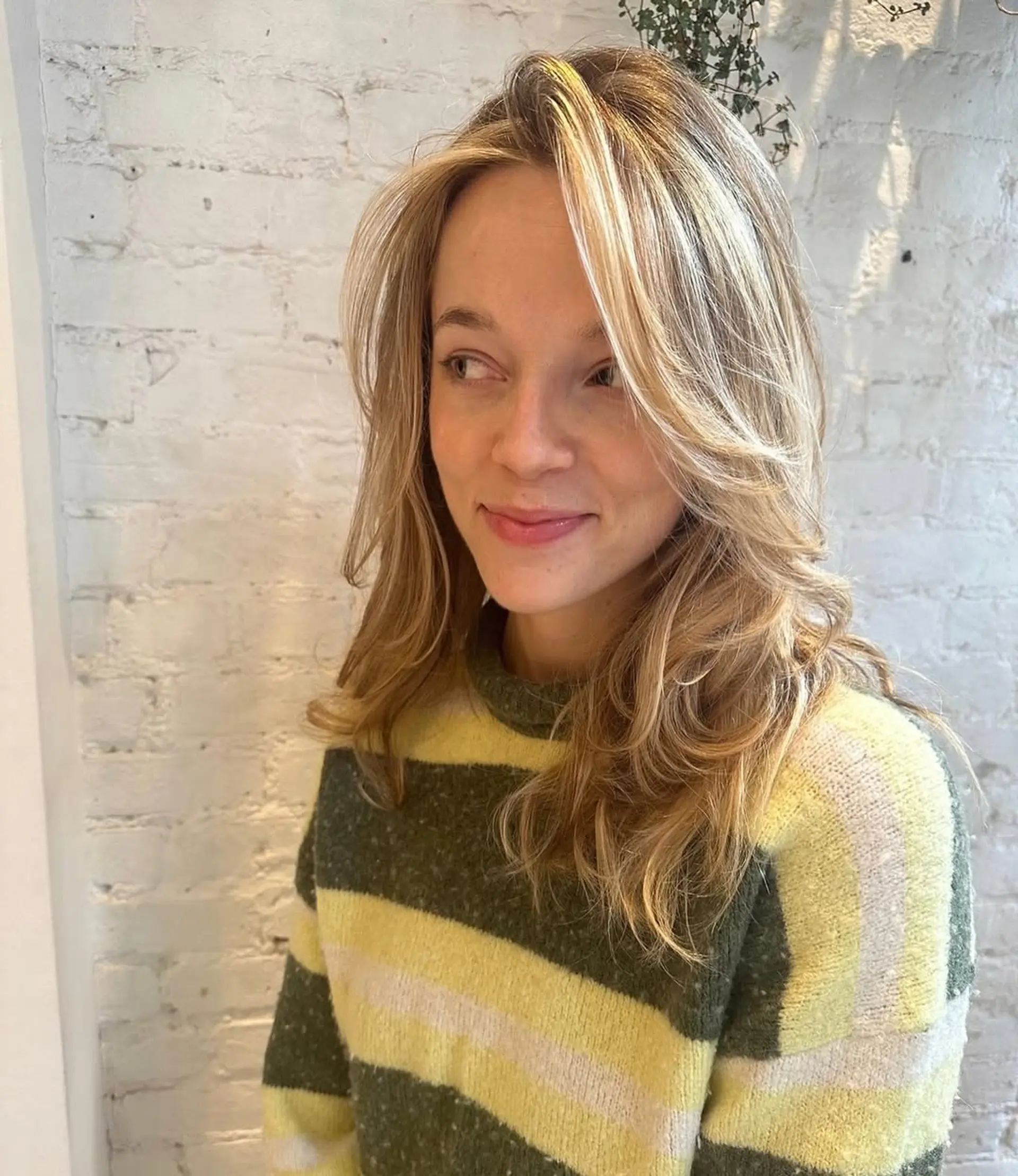 A medium-length wavy hairstyle with curtain bangs and face-framing layers. 2