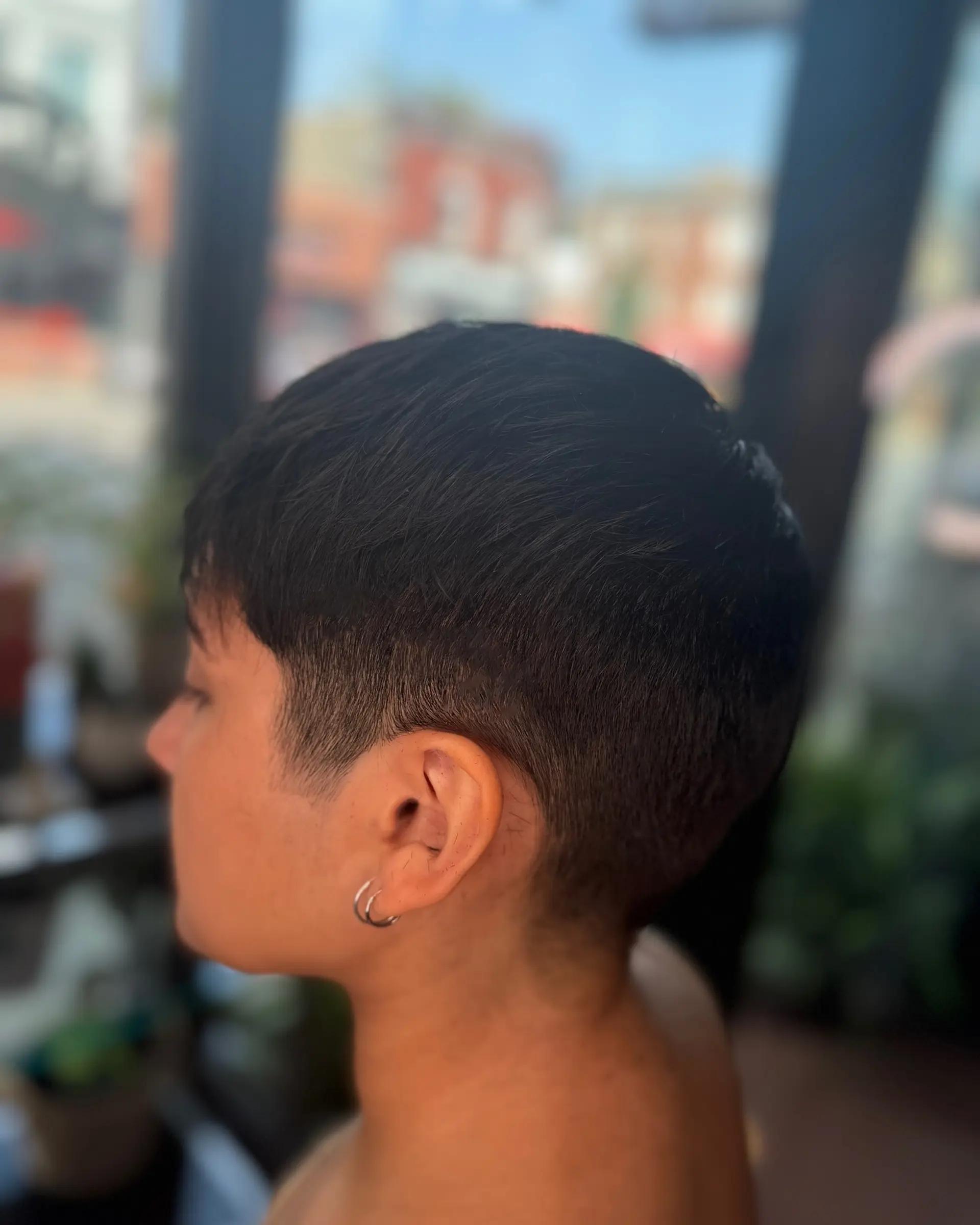A modern cropped pixie cut with finely faded sides and a clean, tapered silhouette around the ear. 1