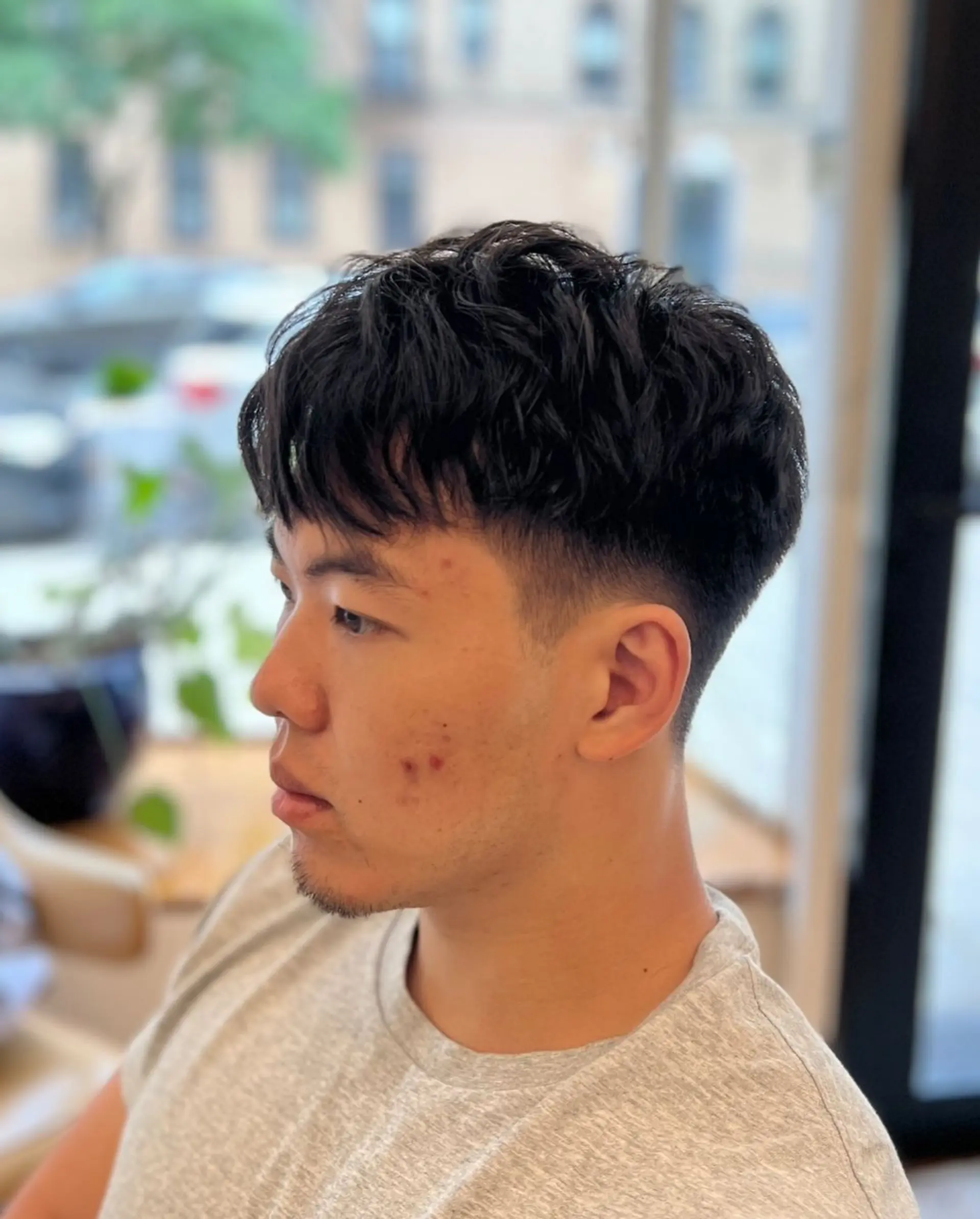 Textured top with natural waves, low fade sides, and short length. 1