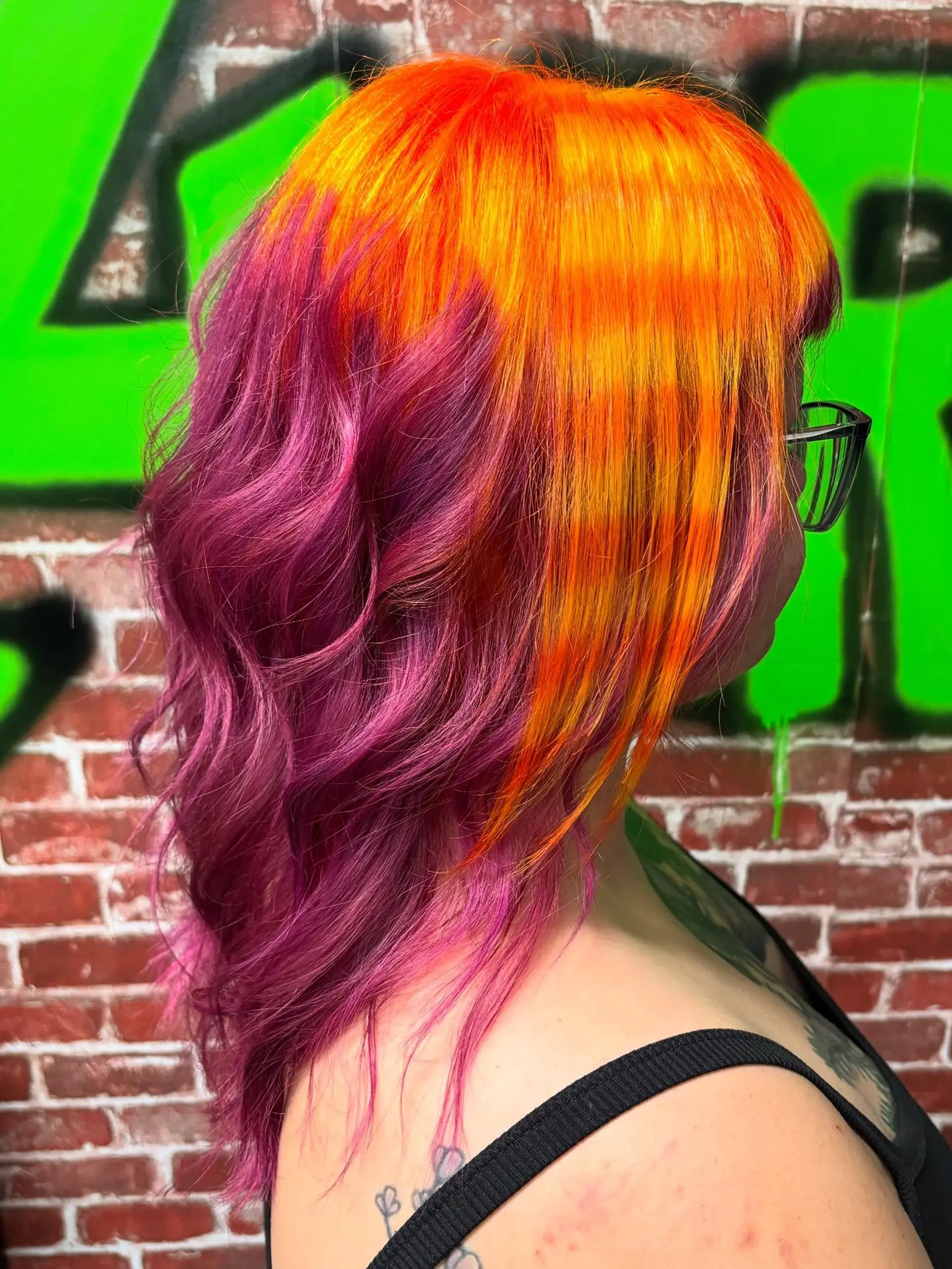 A vibrant creative color look featuring bright neon orange tones on the crown and front layered over deep magenta-purple lengths. 1