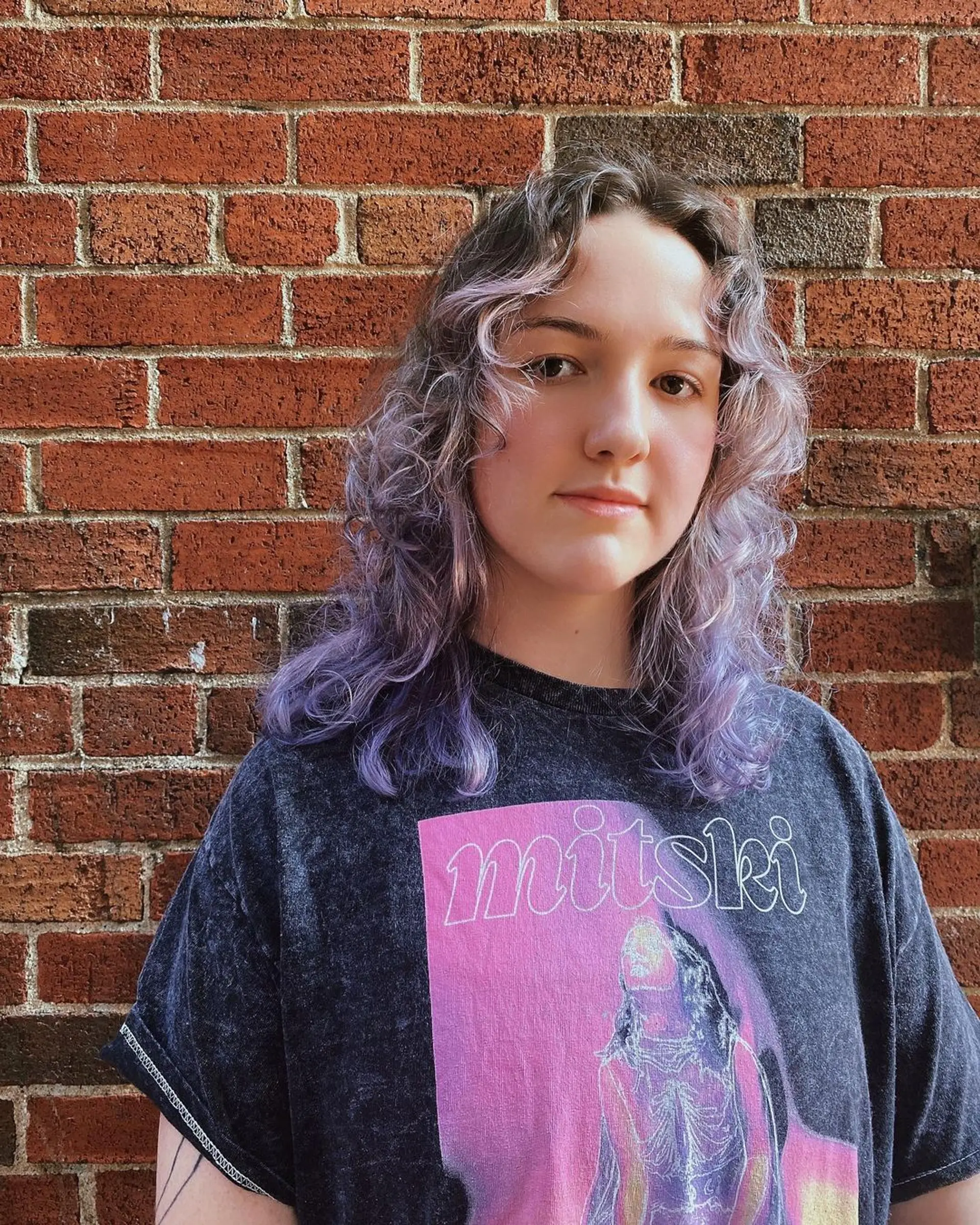 A wavy medium-length hairstyle with light brown roots blending into pastel purple, featuring layered waves and fringe bangs by Coco. 2