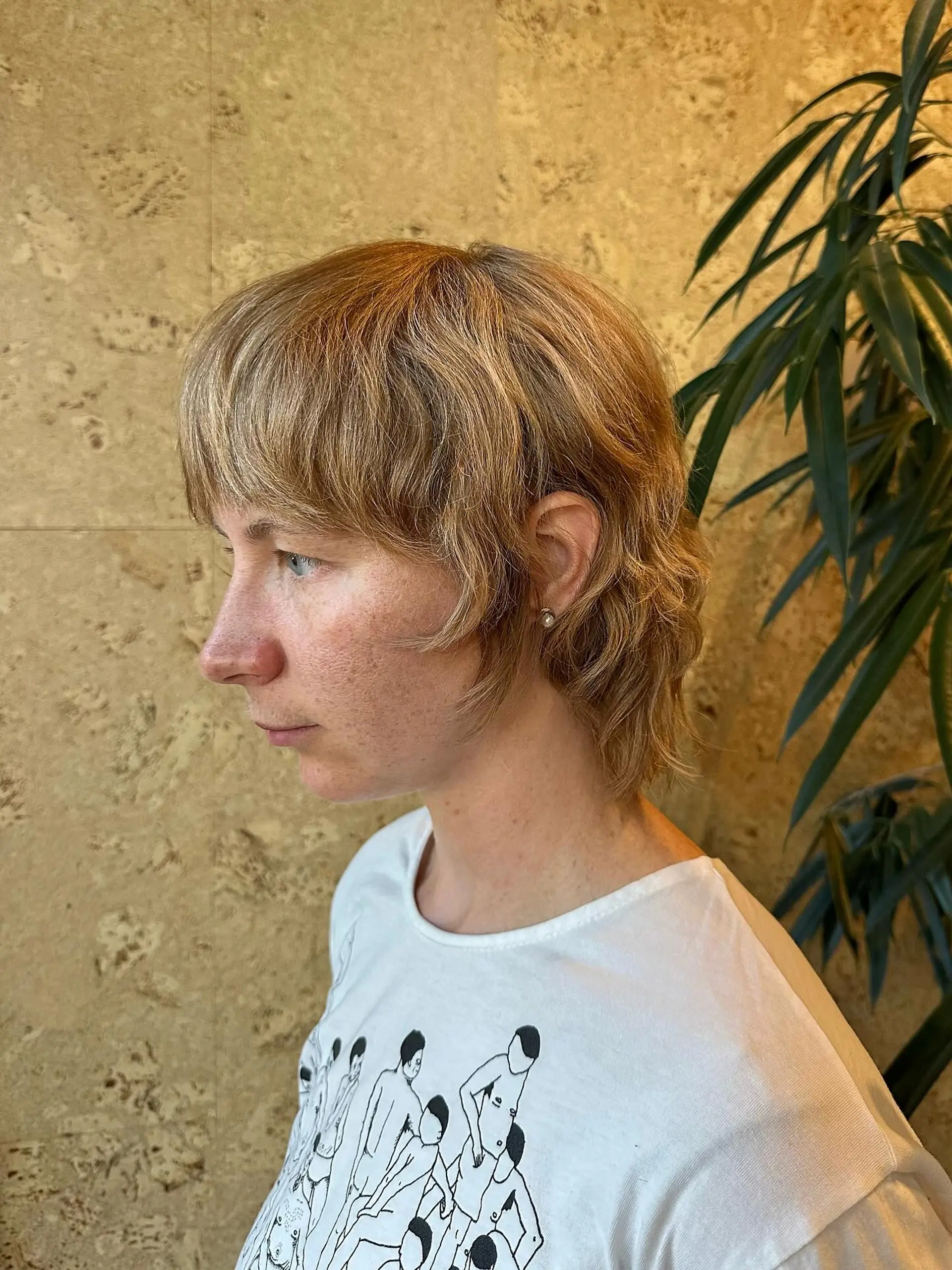 A short shaggy mullet haircut with textured bangs, face-framing layers, and slight natural wave. 1