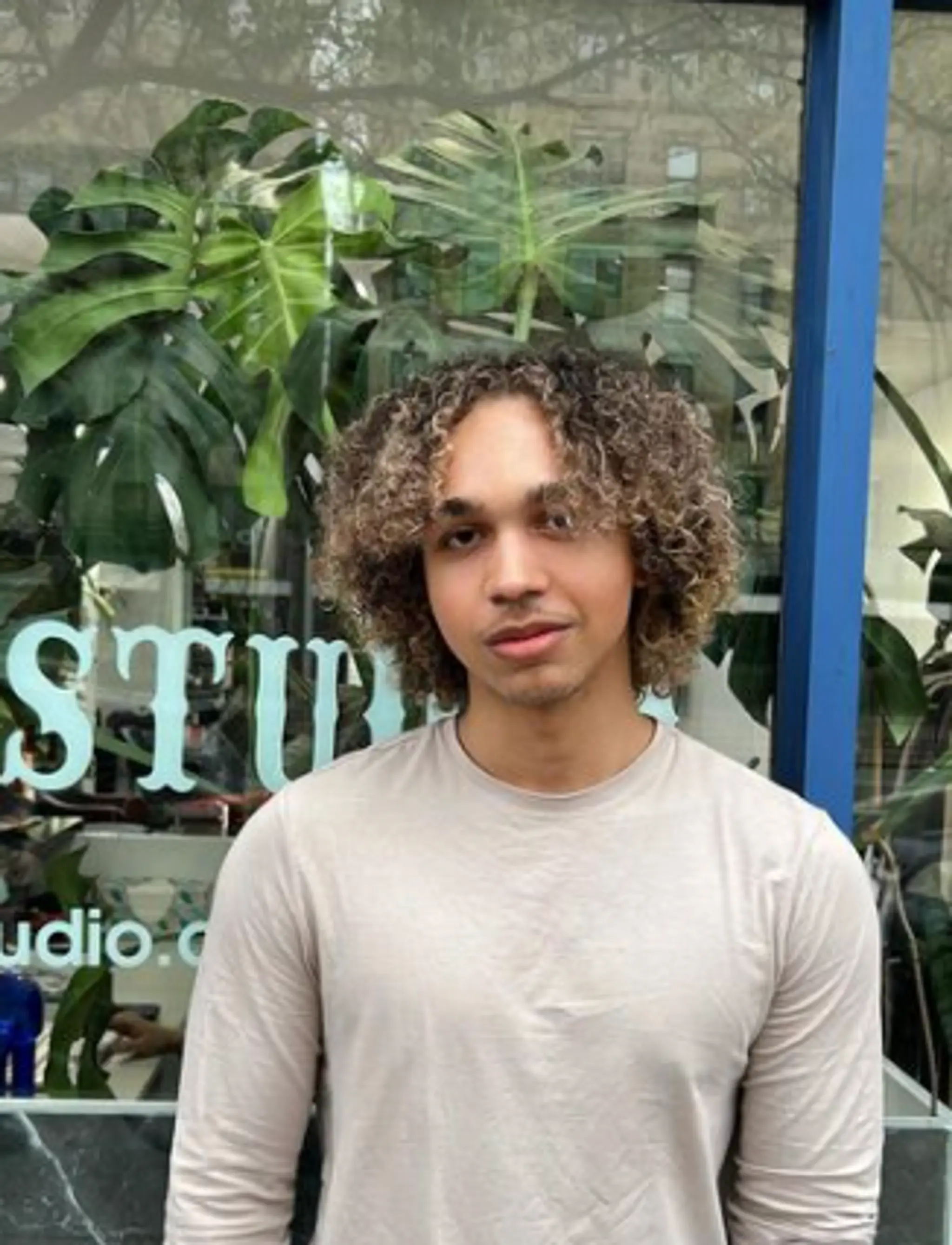 Medium-length curly hairstyle with brown base color and blonde highlights. Loose curls create a natural, voluminous look framing the face with a low maintenance, stylish appearance.