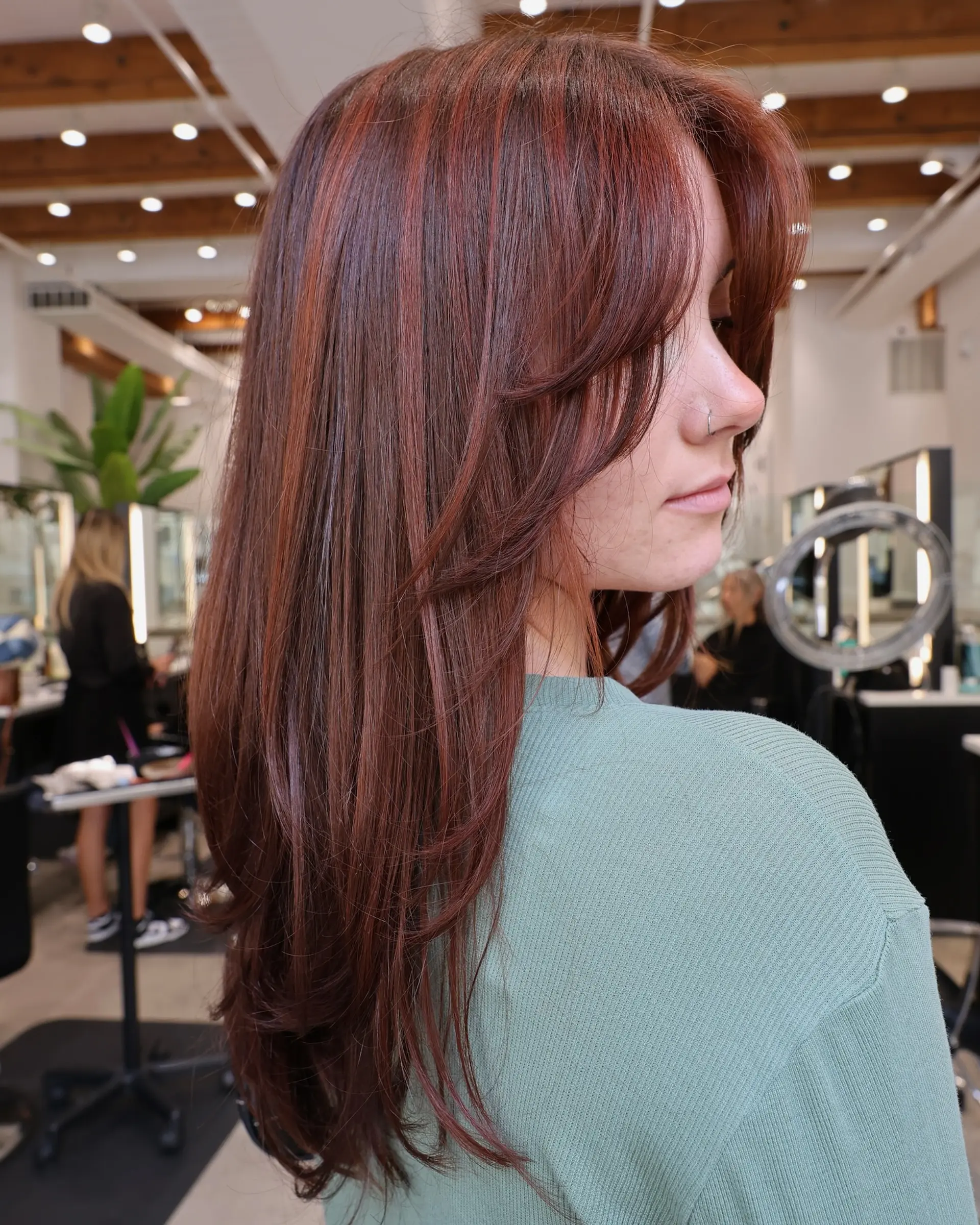 Long layered haircut with face-framing bangs and subtle red highlights. 1