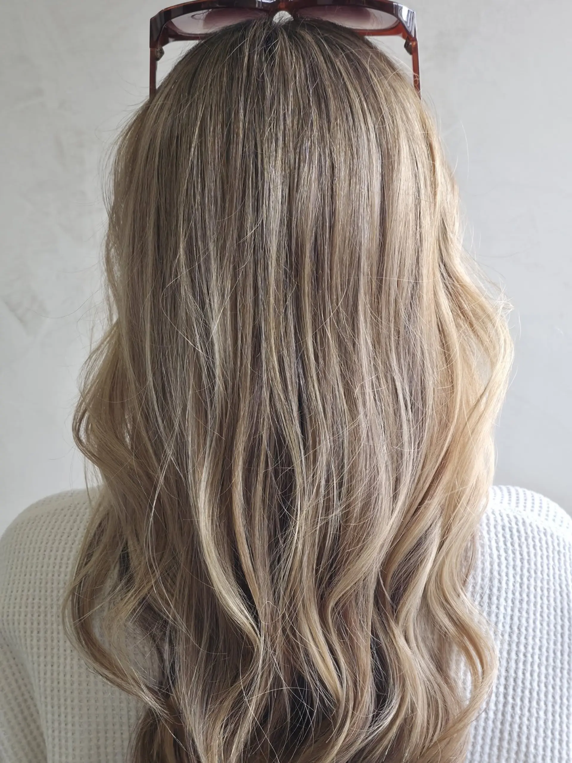 Long beige blonde hair with seamless highlights and soft, loose waves cascading down the back. 1