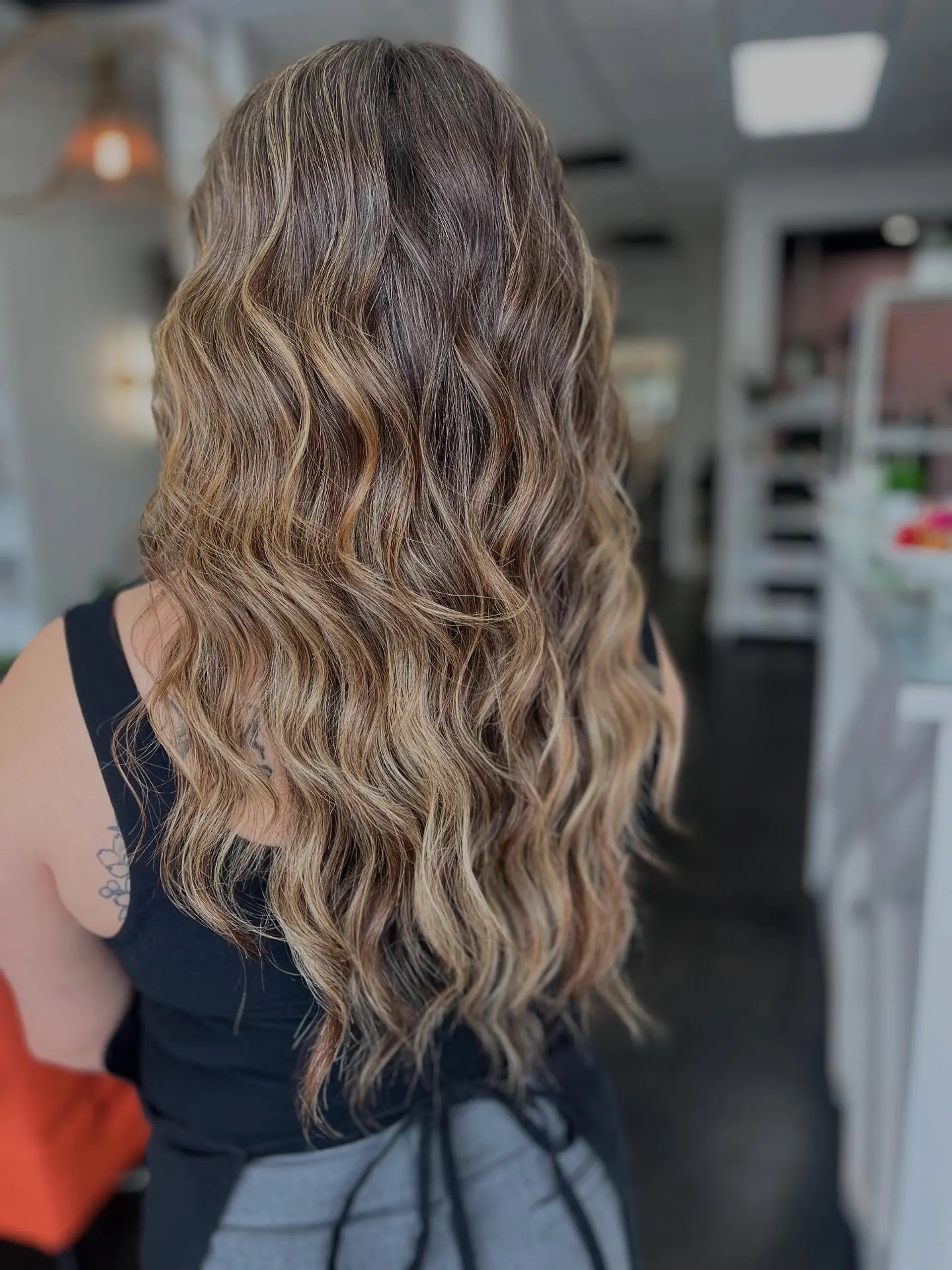 Long hair featuring a seamless, blended blonde balayage styled with soft, cascading waves. 1