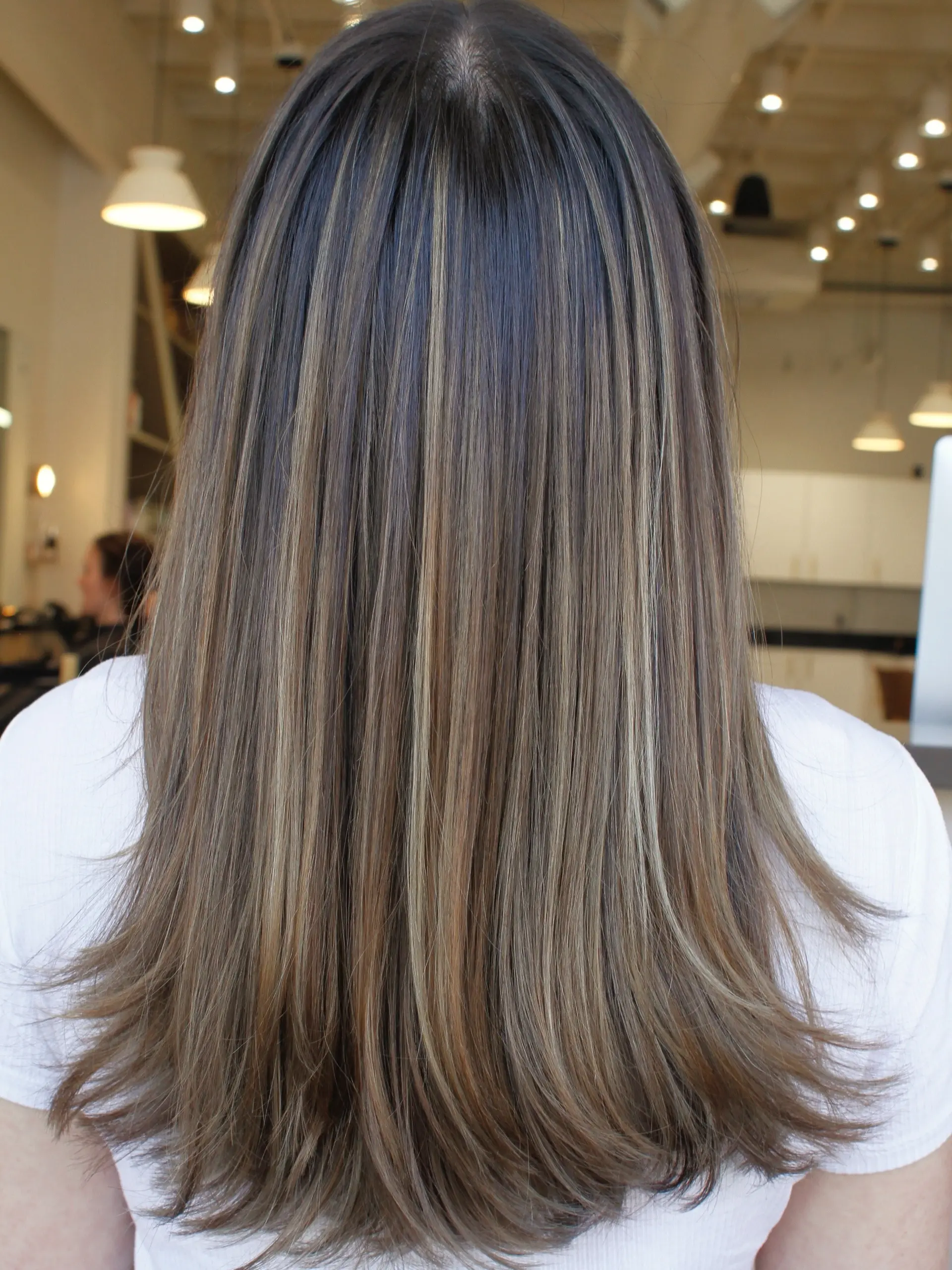 Straight, long brunette hair accented with finely blended cool-toned blonde and light brown highlights. 1