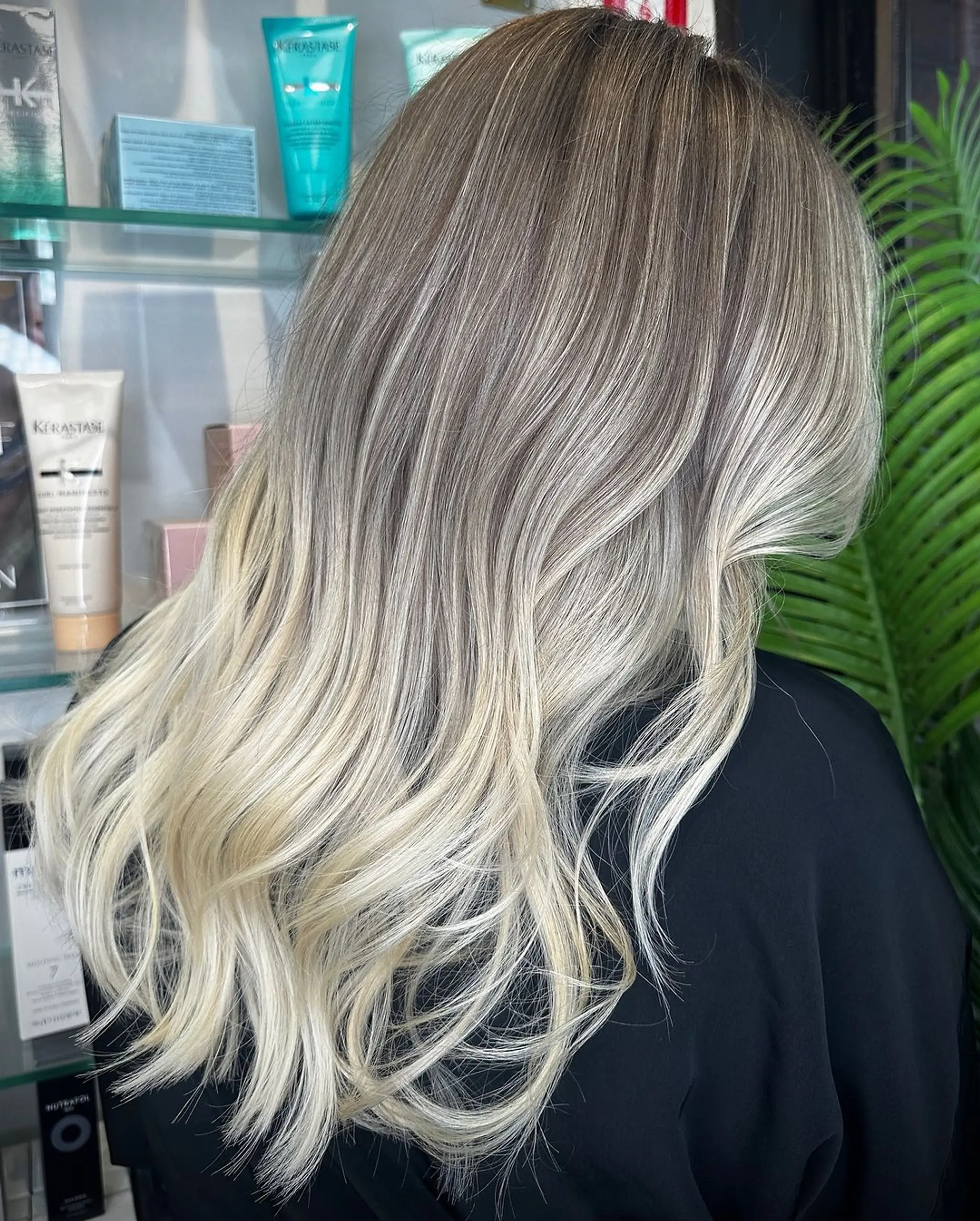 Long, wavy hair with an ombre transition from dark blonde to platinum blonde, styled in loose waves with a soft, natural texture.