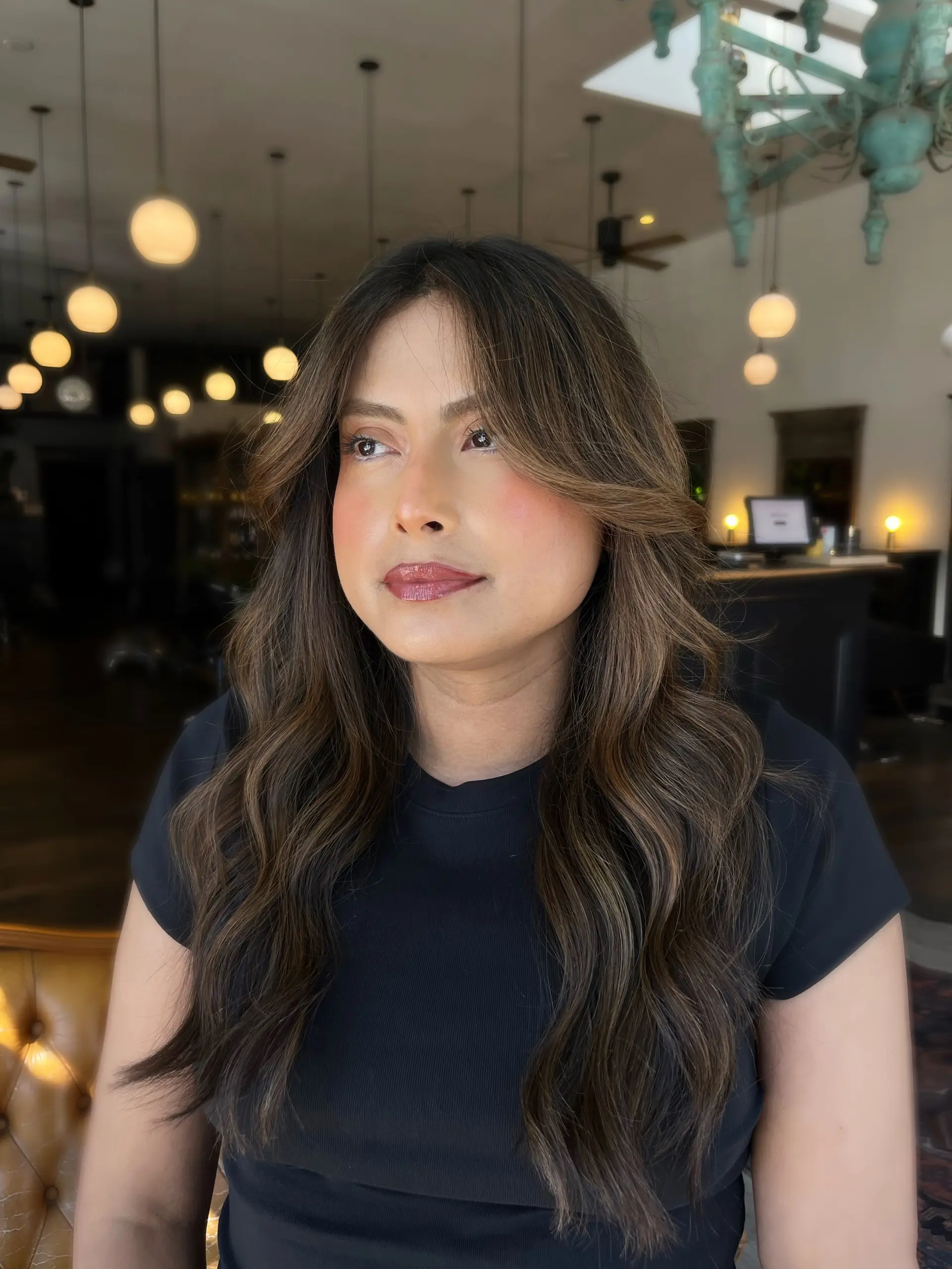 Long dimensional bronde hair styled with soft, voluminous waves and face-framing curtain layers. 1