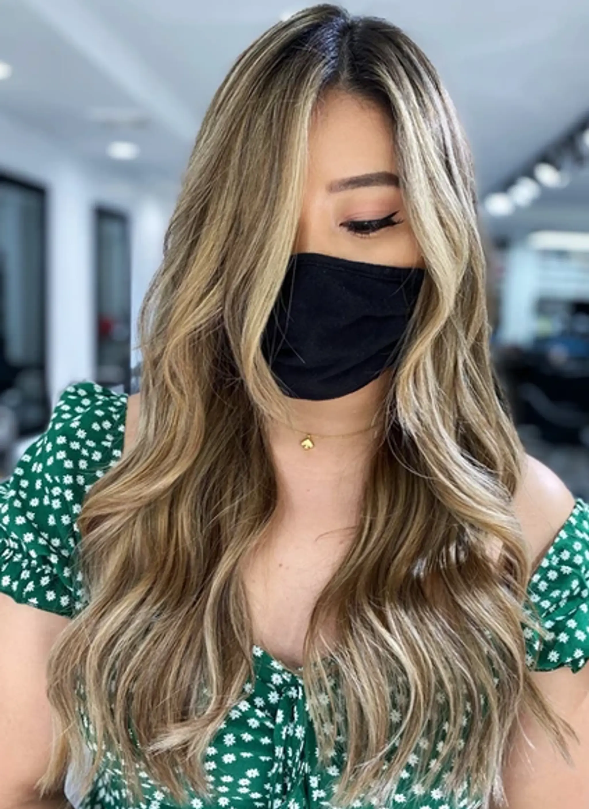 Long, wavy hairstyle with balayage in blonde and light brown hues. Loose, flowy waves with face-framing layers and a middle part.