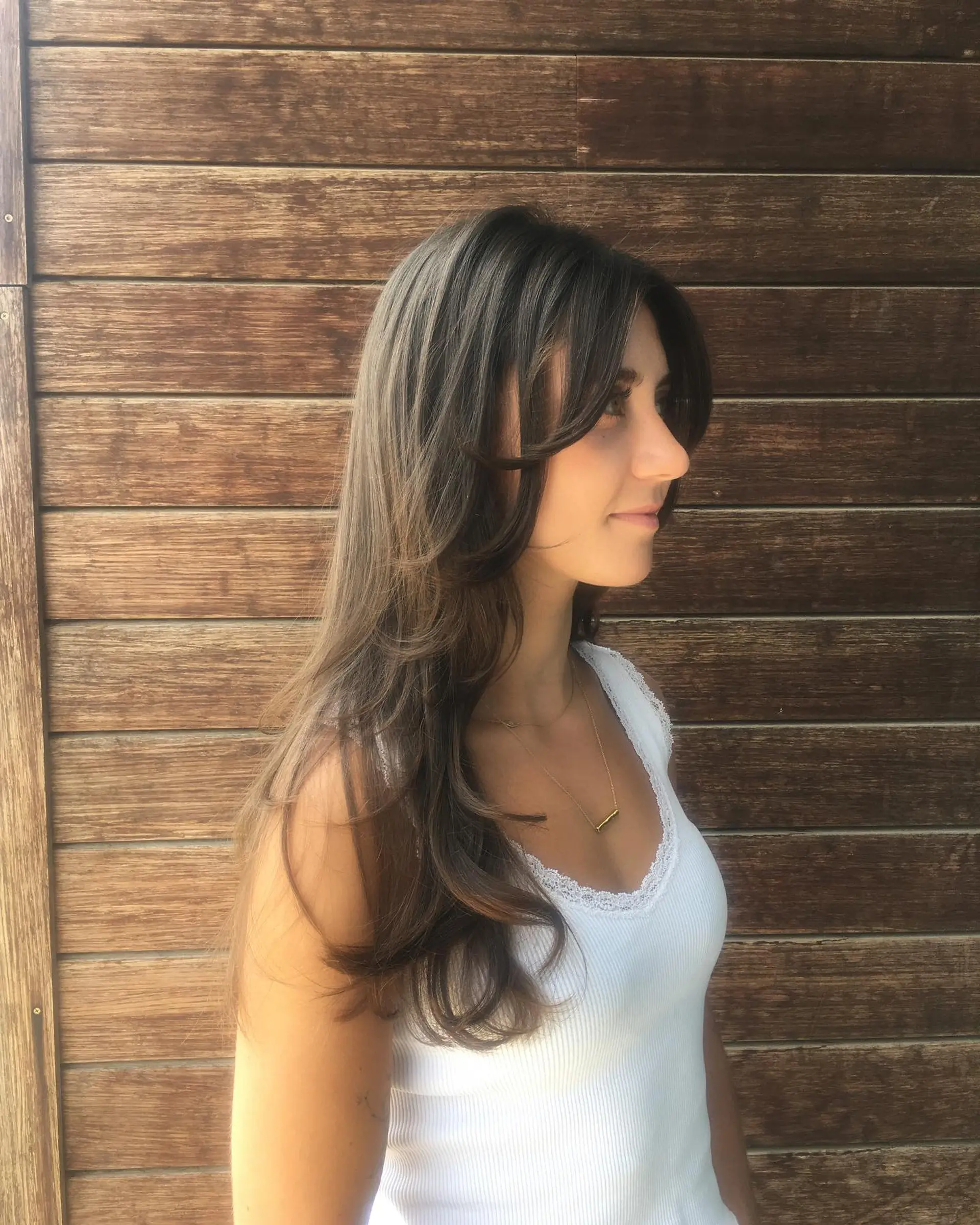 Long brunette hair styled with soft, face-framing curtain bangs and subtle layers. 1