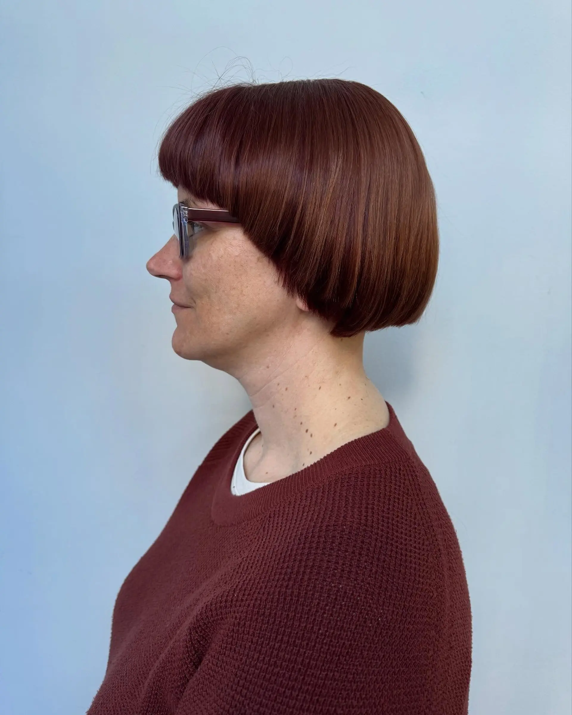 A sleek, geometric precision bob haircut featuring curved blunt bangs and a sharp, rounded perimeter. 1