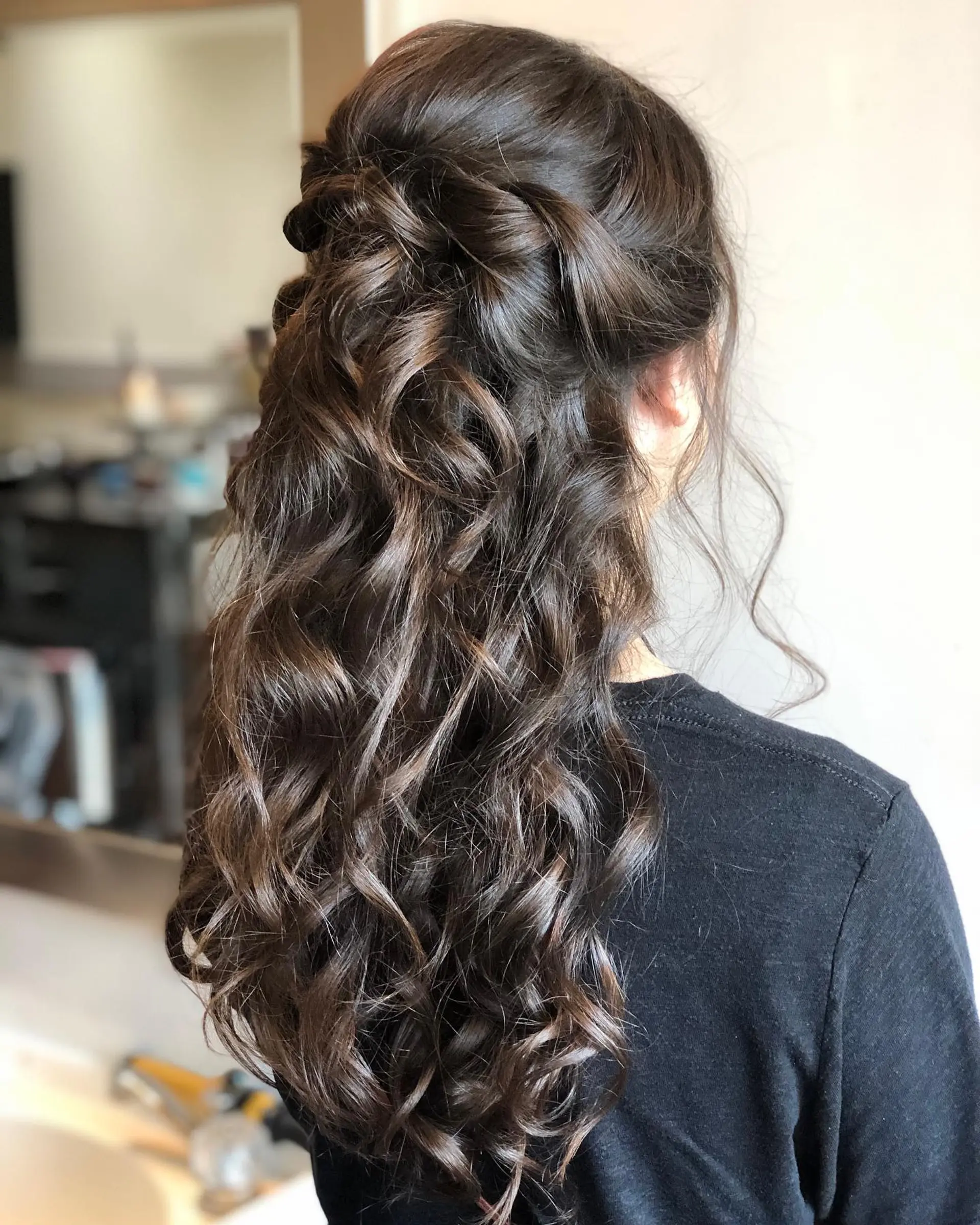 A romantic half-up, half-down hairstyle with soft crown twists and cascading, defined curls. 1