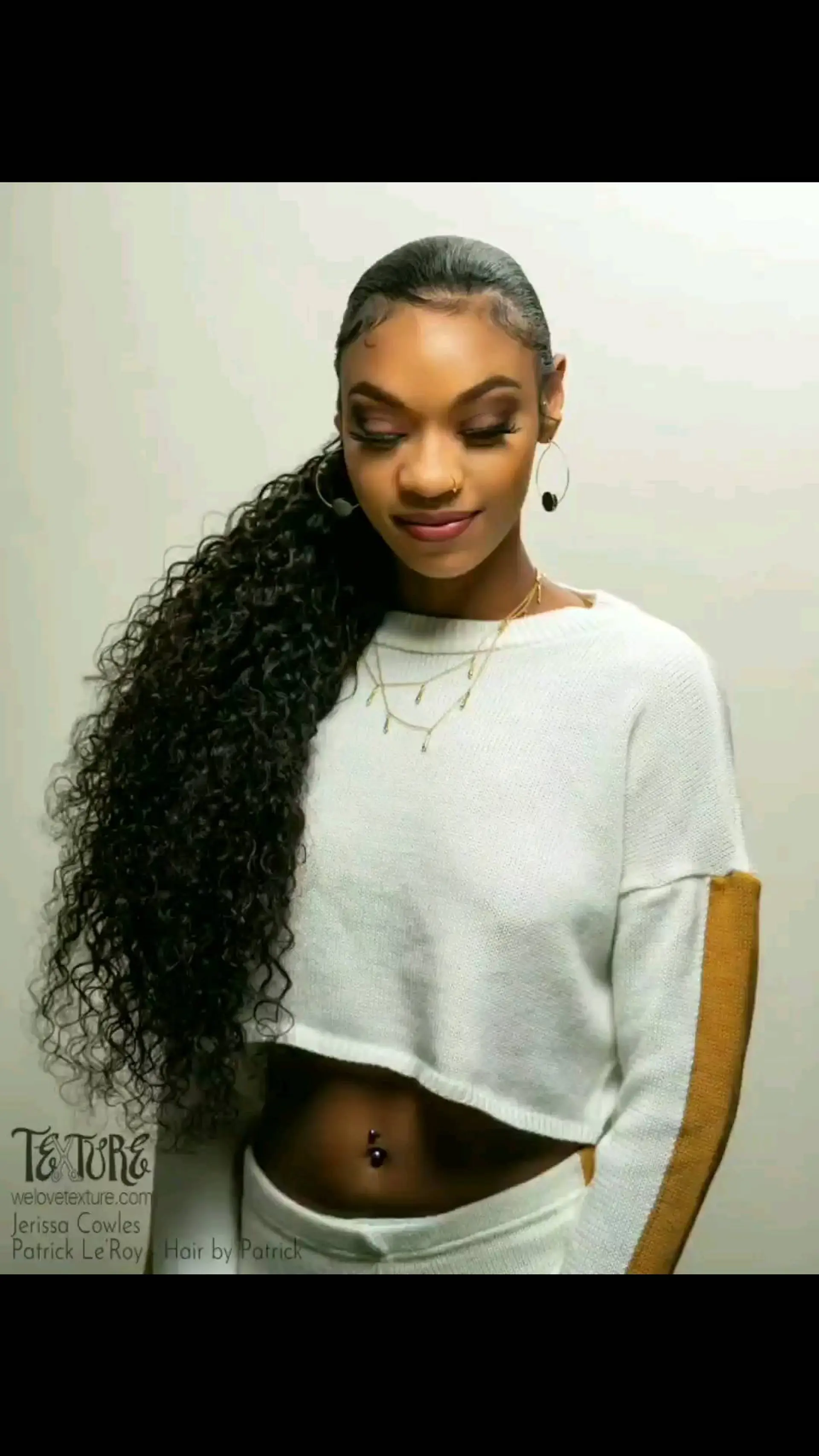 A sleek, slicked-back ponytail falling over the shoulder with voluminous defined curls and styled baby hair along the hairline. 1