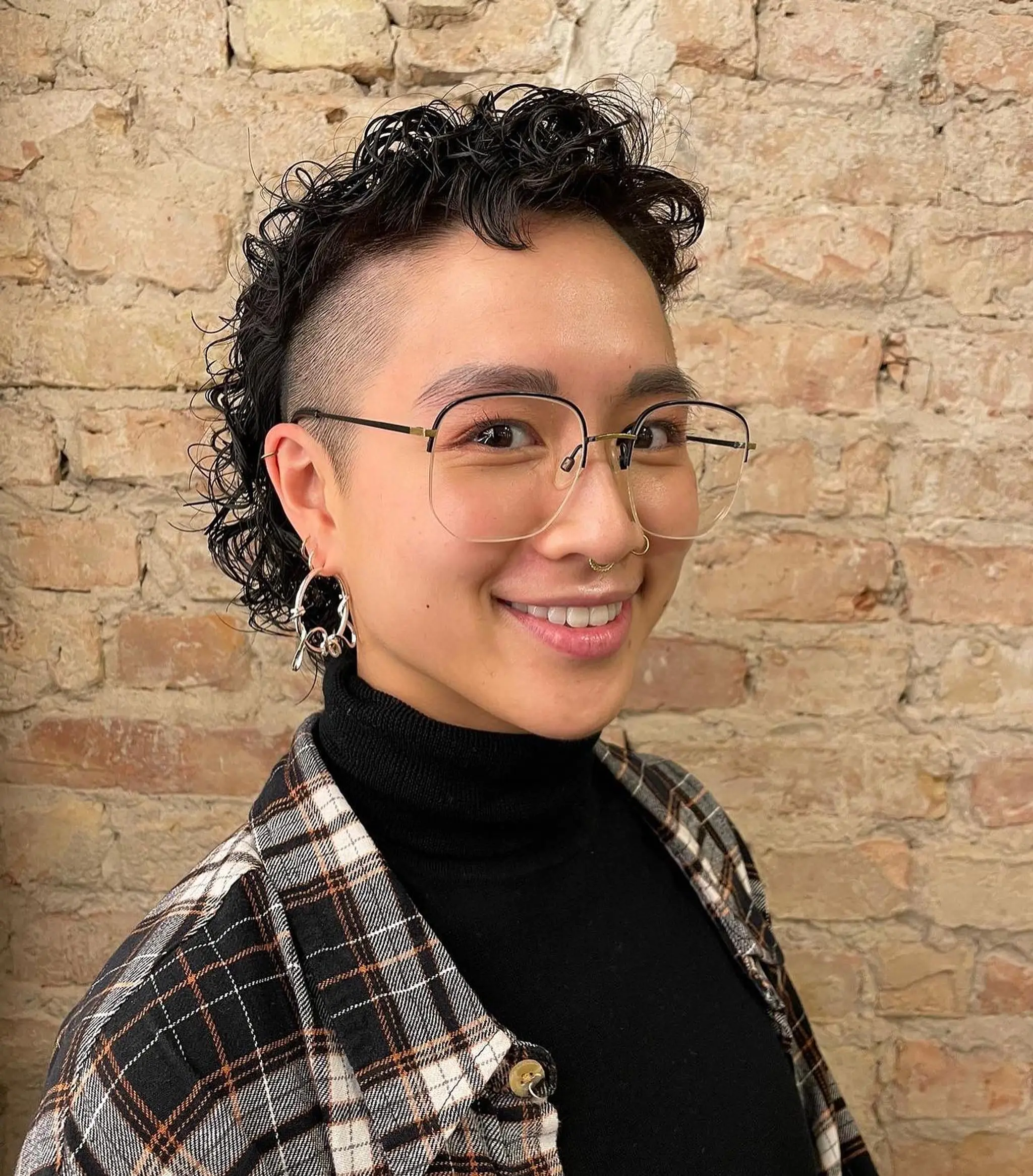 An edgy curly hawk with shaved sides and short, well-defined black curls on top.
